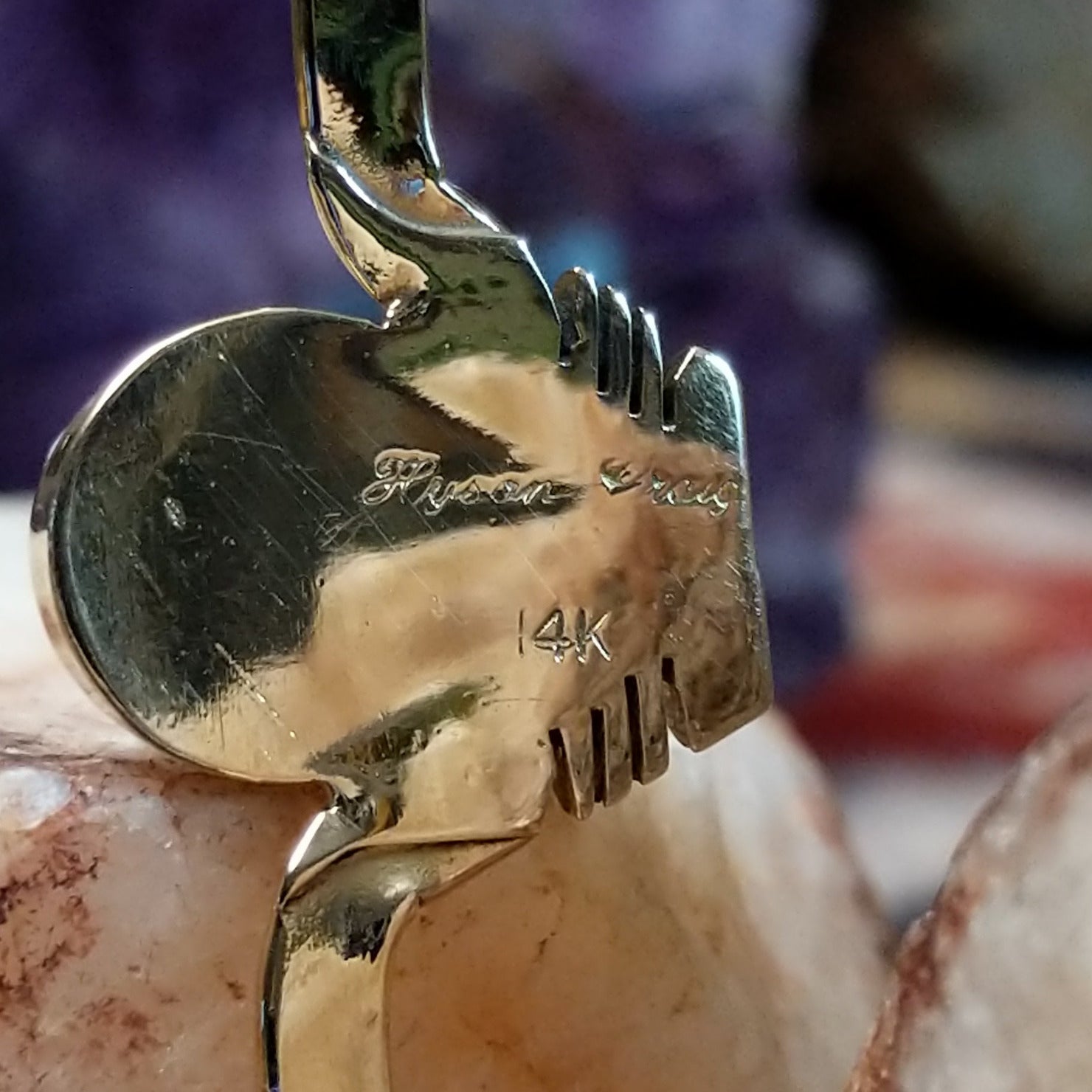 Close up of artist's stamped signature and stamped 14K, indicating 14 karat gold construction.