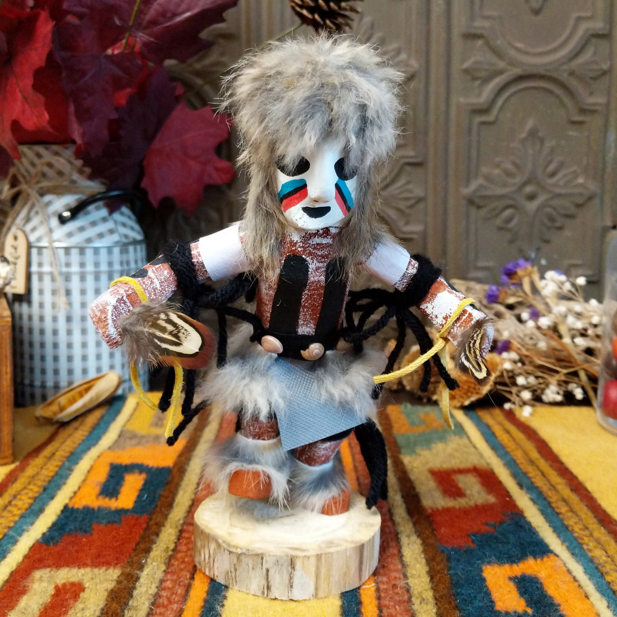 Navajo Field House Kachina doll with gray fur headdress, white painted face, red and turquoise cheek markings, and light blue fabric apron.