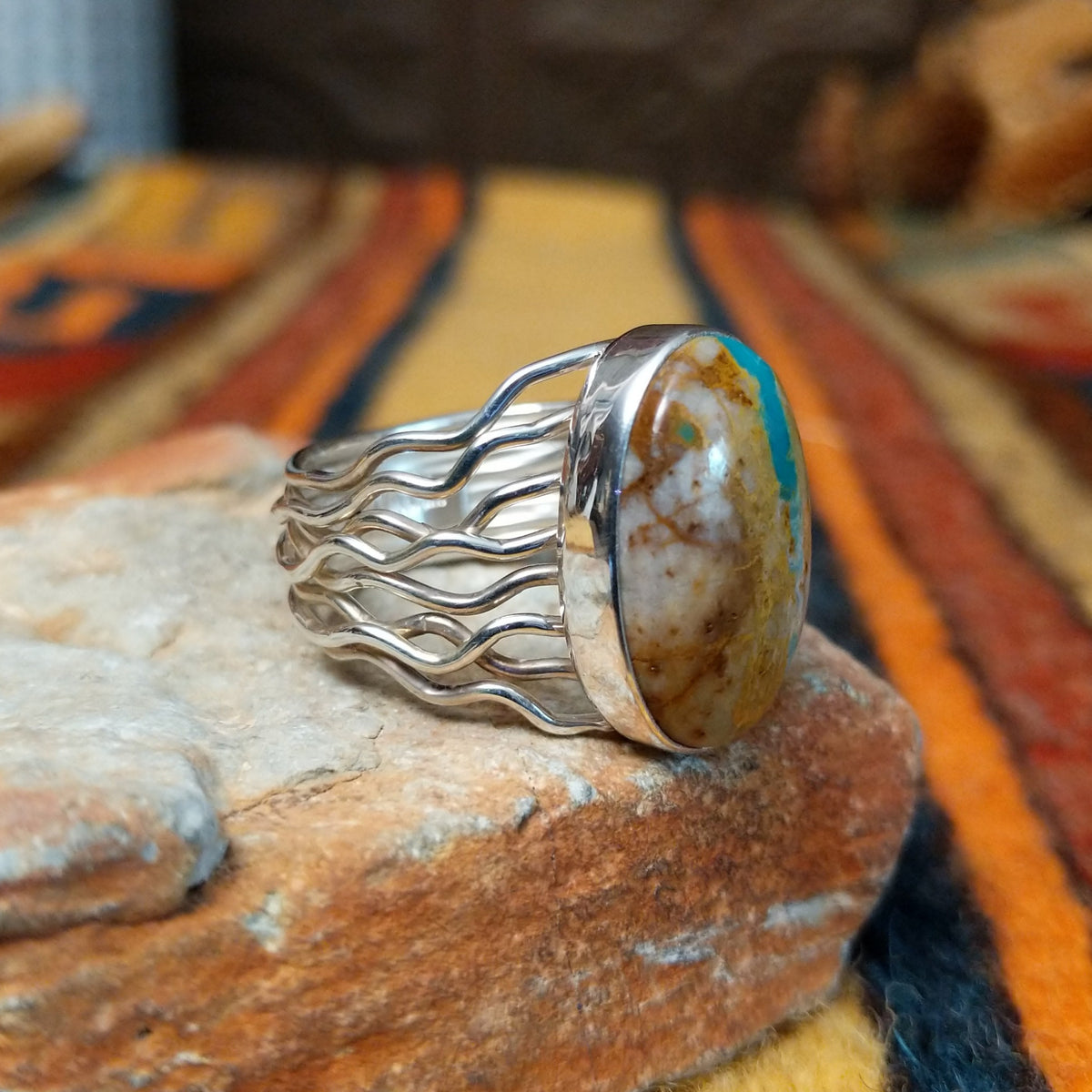 Boulder Turquoise Strand Ring by Angela Martin featuring a natural turquoise stone set in sterling silver, size 8, approximately 0.75 inches long and 0.875 inches wide. Handcrafted jewelry piece with distinctive turquoise patterns; side view.