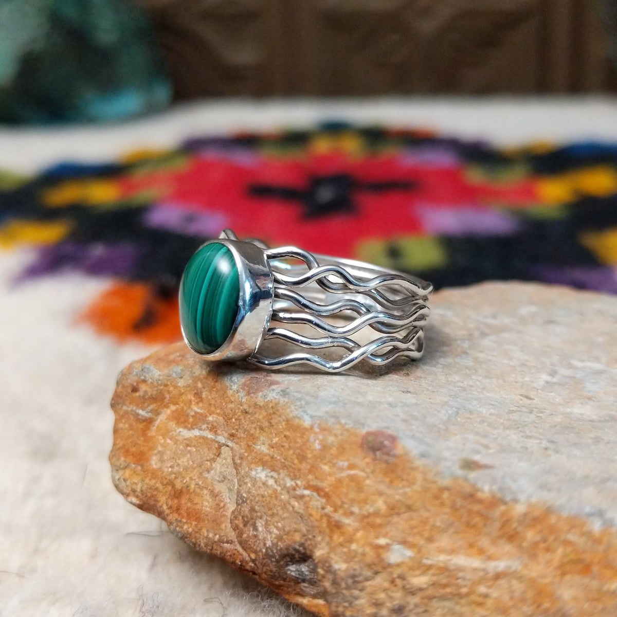 Malachite ring by Angela Martin with an oval banded stone and multi-strand wavy silver band.