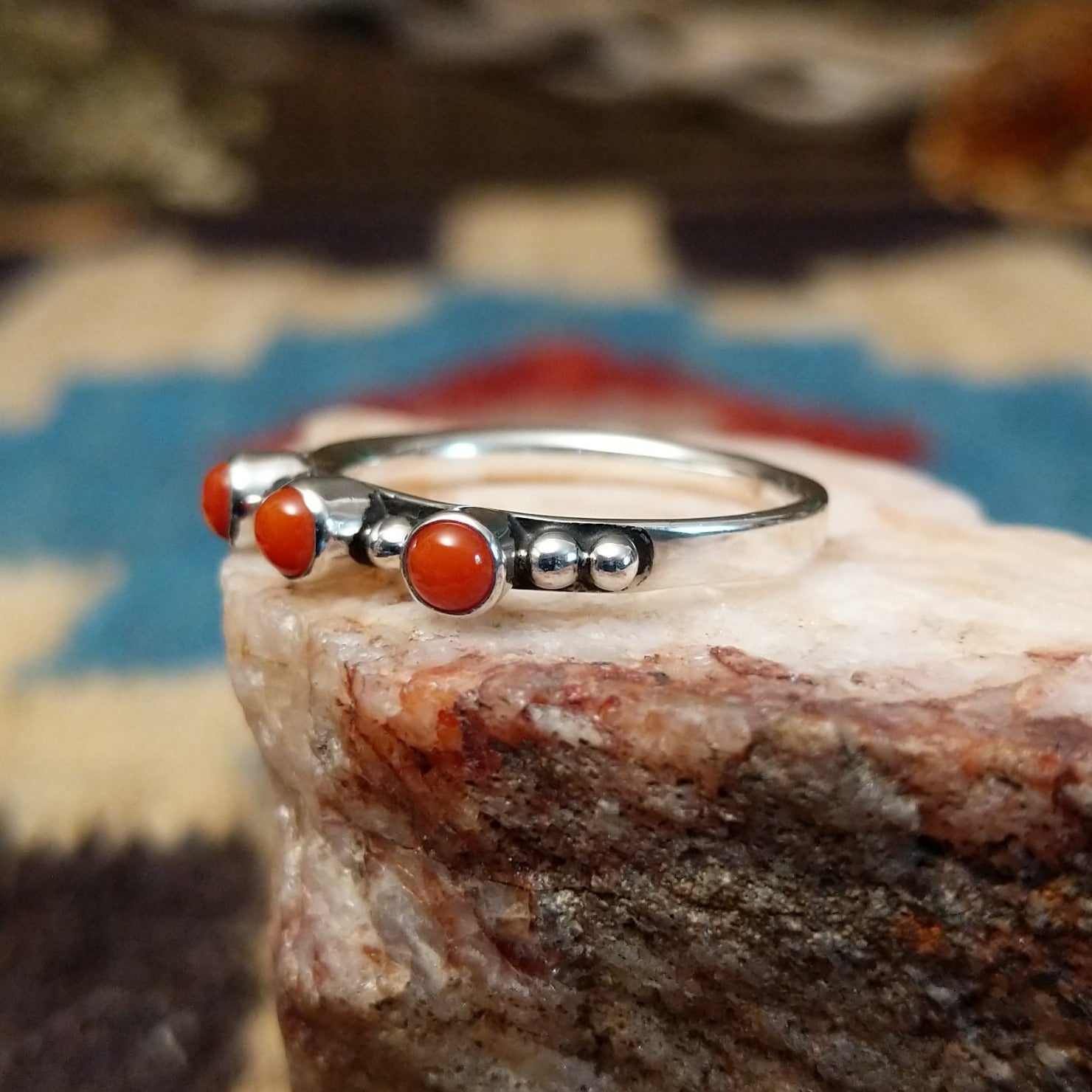 Sterling silver ring with coral set in three small, round bezels.