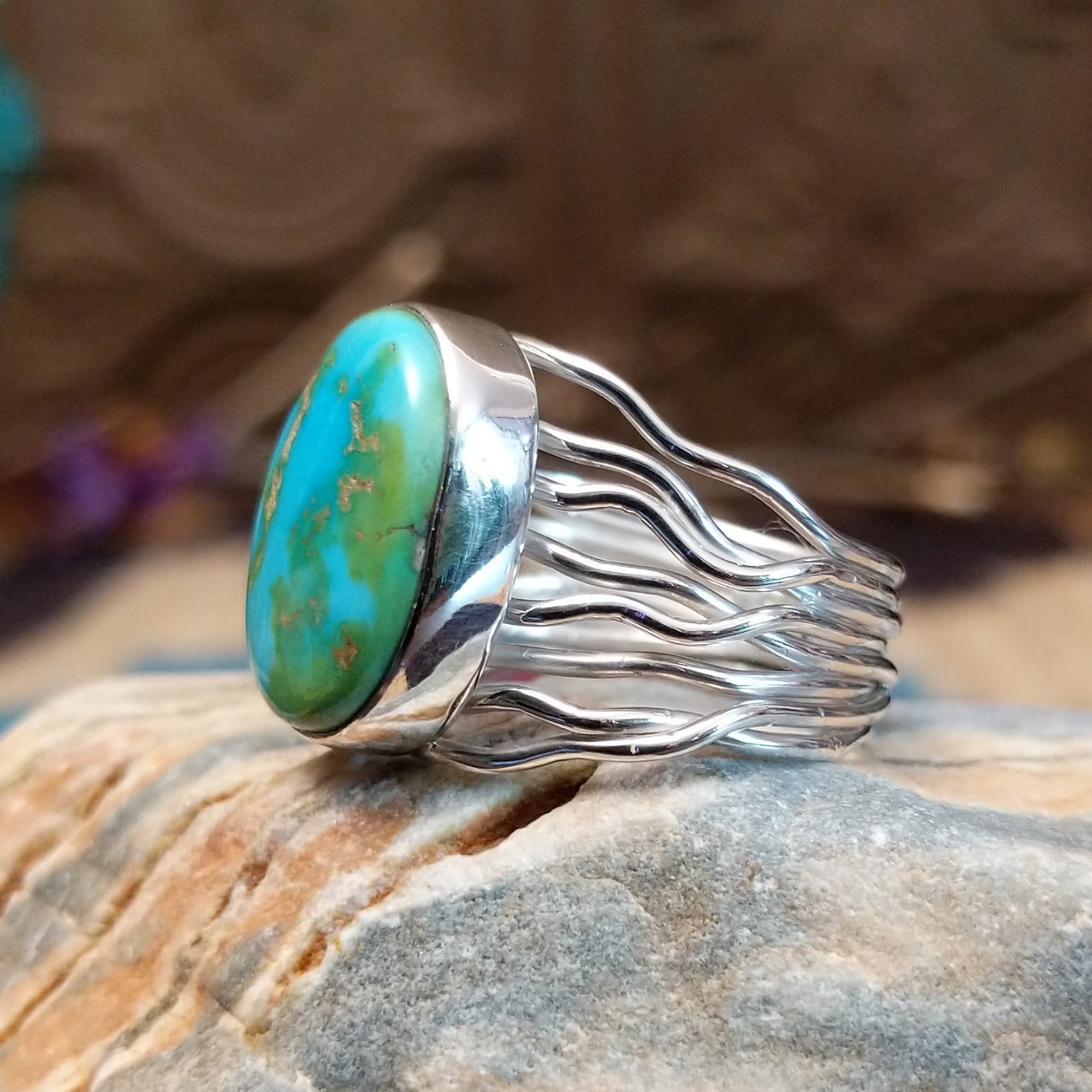 Sterling silver ring with Sonoran gold turquoise set in an oval bezel and band with strands of silver.