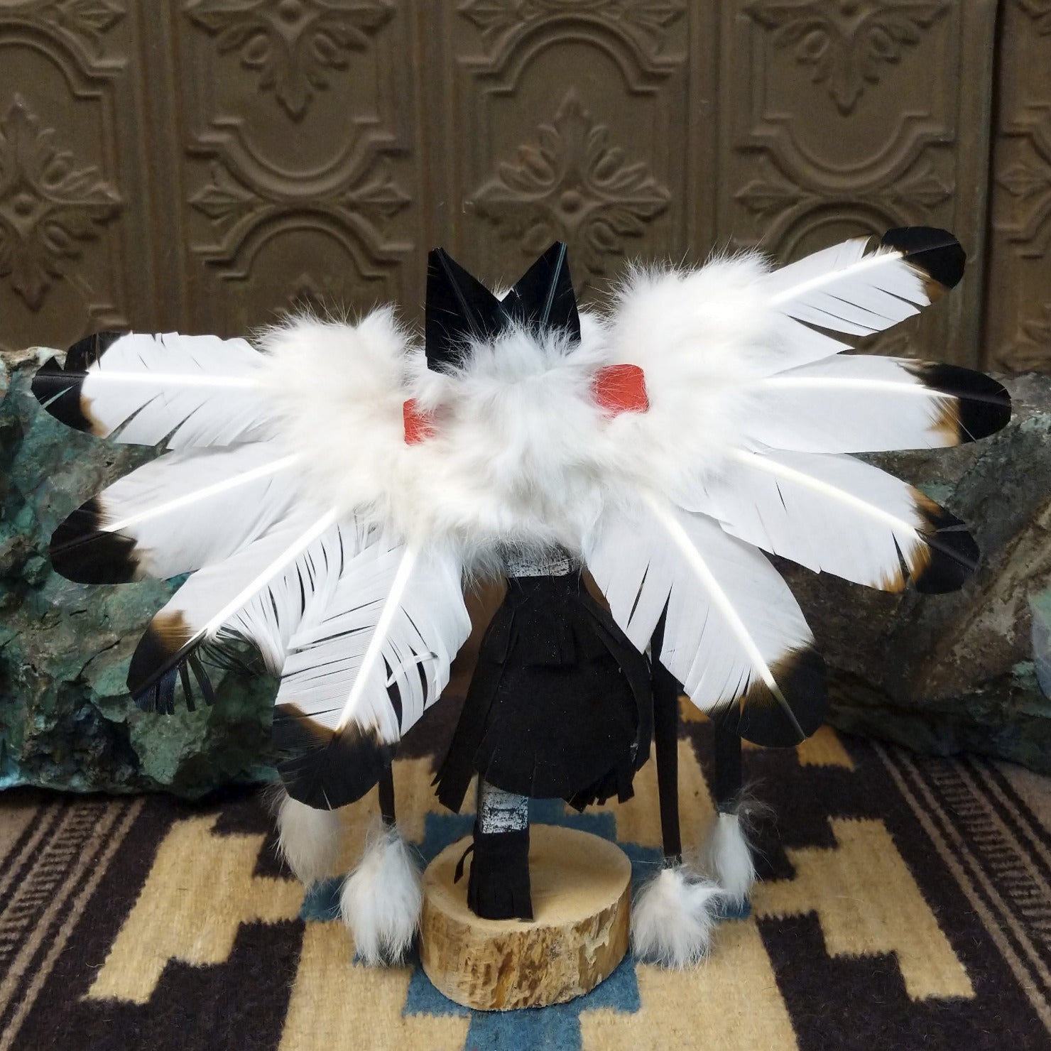 Navajo-made eagle kachina doll by M. C. with white feathered wings, blue mask, yellow beak, and black garments.