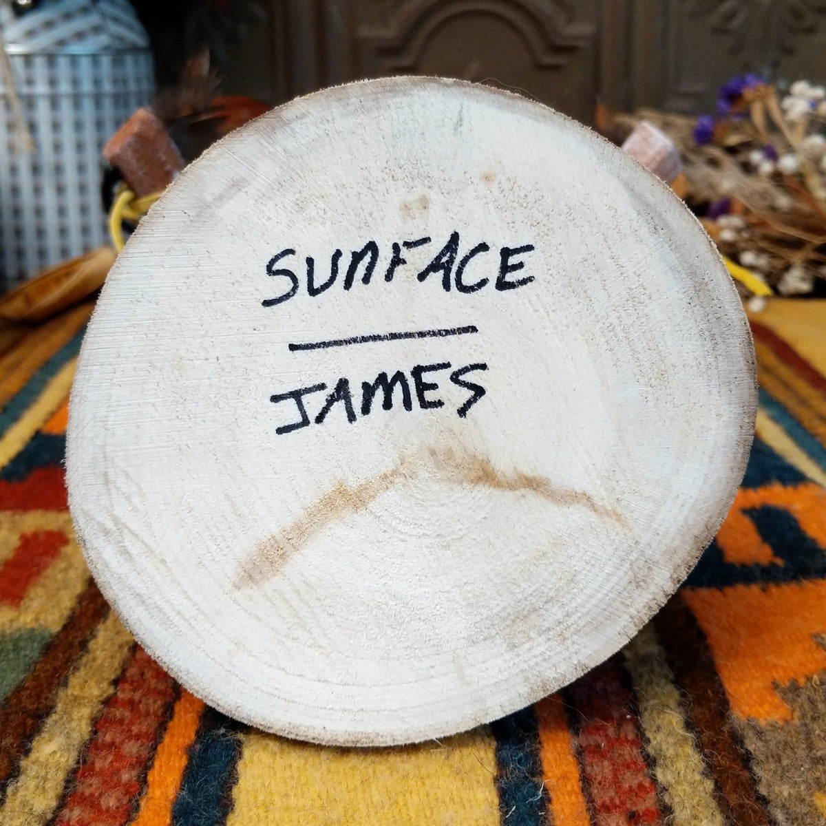 Underside of Navajo Sunface Kachina doll base with handwritten figure name and artist surname.