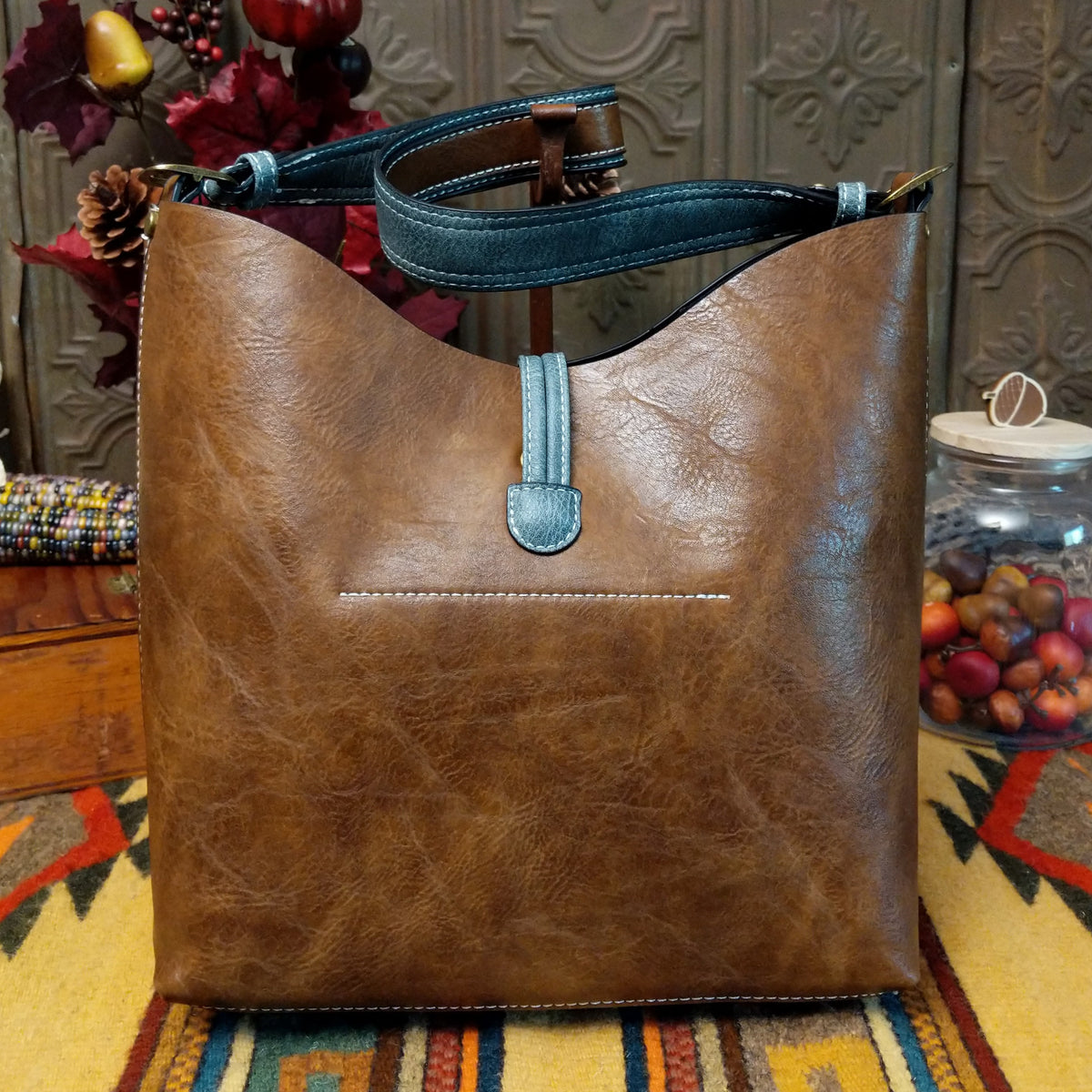 Alexa Handbag by Liz Soto featuring a tall structured silhouette, decorative contrast stitching, vertical center detailing, large wrapped circular accent, and wide shoulder strap; back.