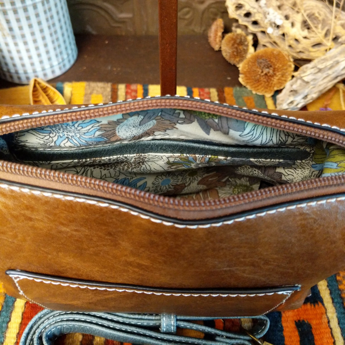 Alexa Handbag by Liz Soto featuring a tall structured silhouette, decorative contrast stitching, vertical center detailing, large wrapped circular accent, and wide shoulder strap; interior.