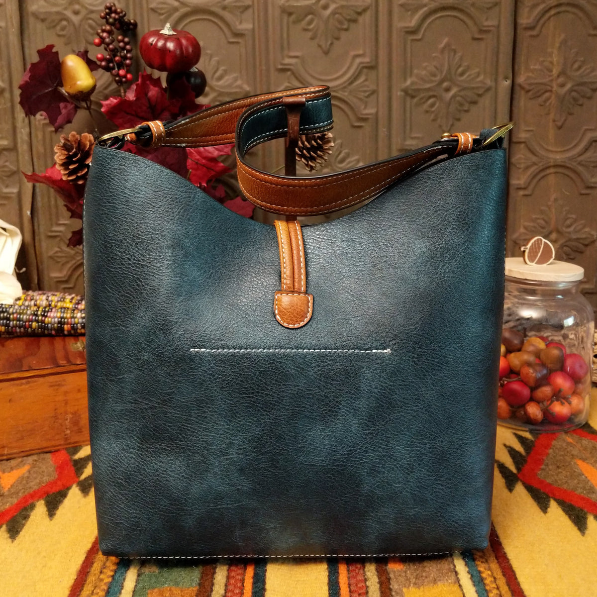 Alexa Handbag by Liz Soto featuring a tall structured silhouette, decorative contrast stitching, vertical center detailing, large wrapped circular accent, and wide shoulder strap; back.