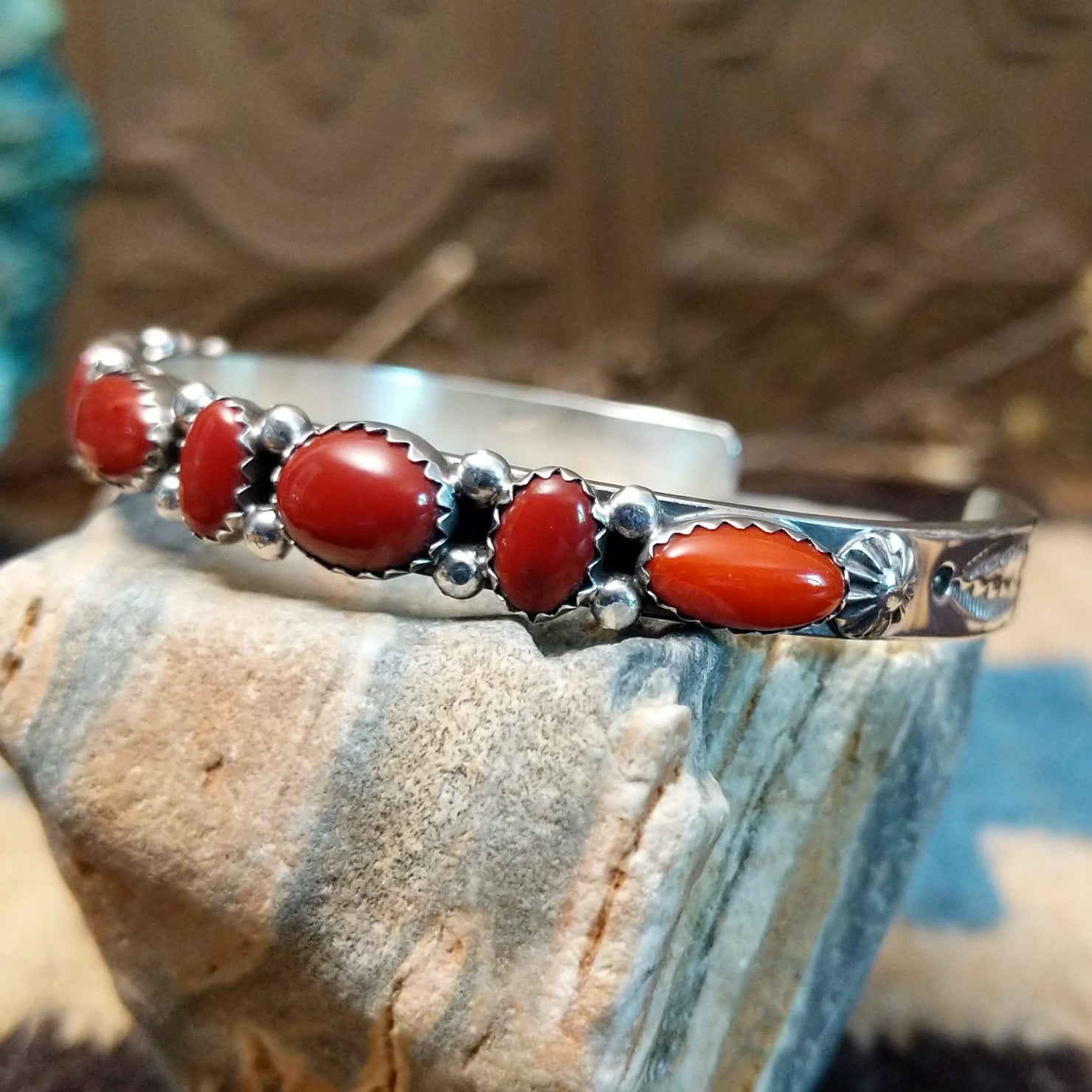 Sterling silver cuff with coral set in notched bezels that alternate across the surface of the band.