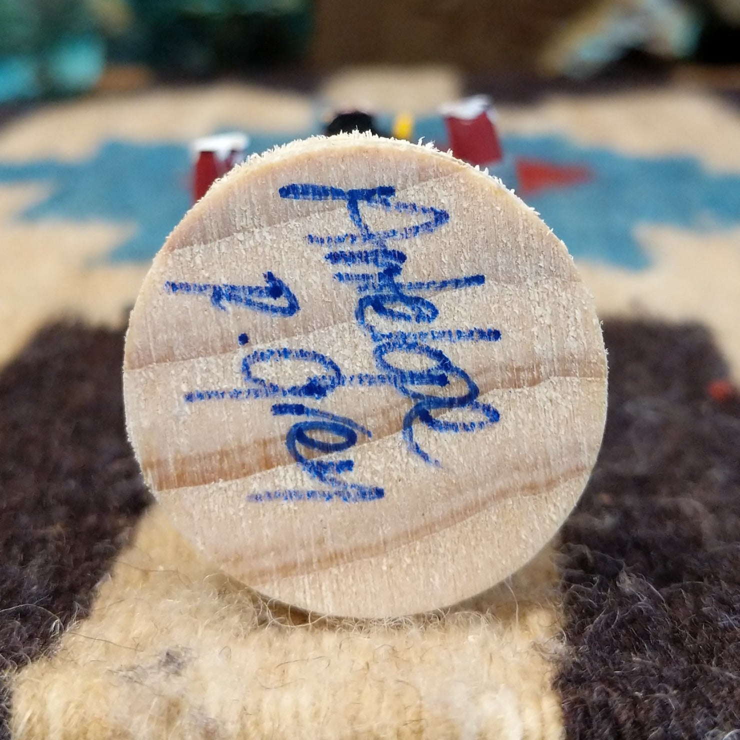 Underside of antelope mini kachina doll showing handwritten signature and label on wood base.