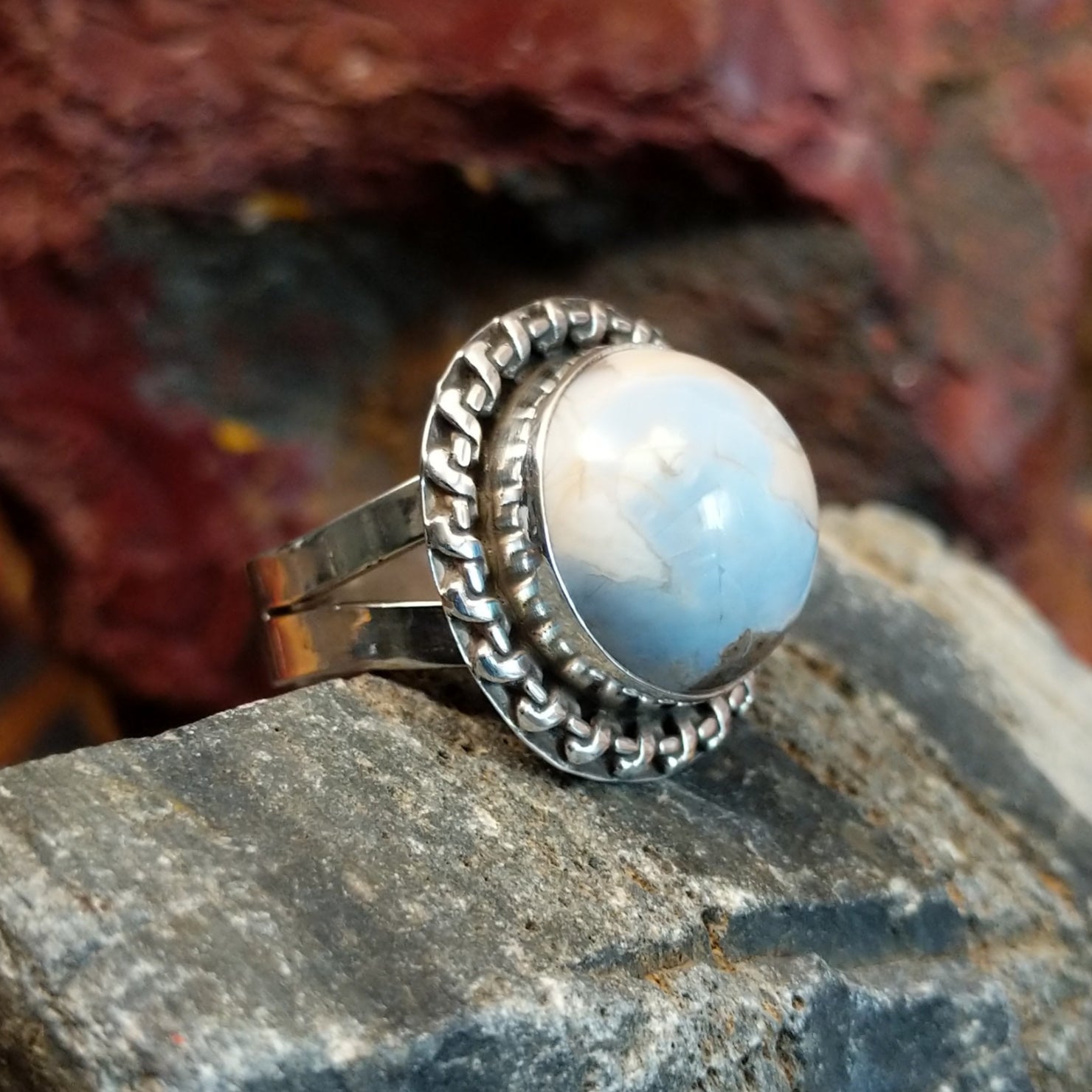 Ring features a large, dome-shaped blue opal set in a twisted silver band.