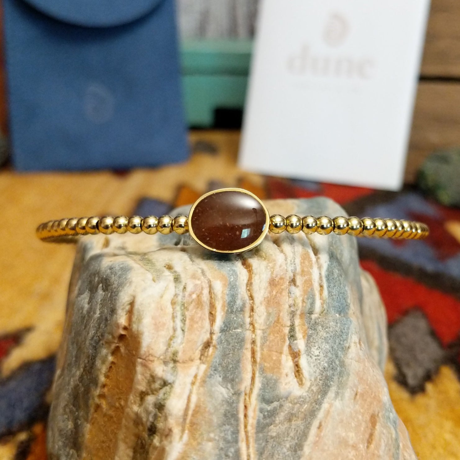Beaded cuff bracelet with a gold-plated brass frame, featuring an oval sand-filled center.