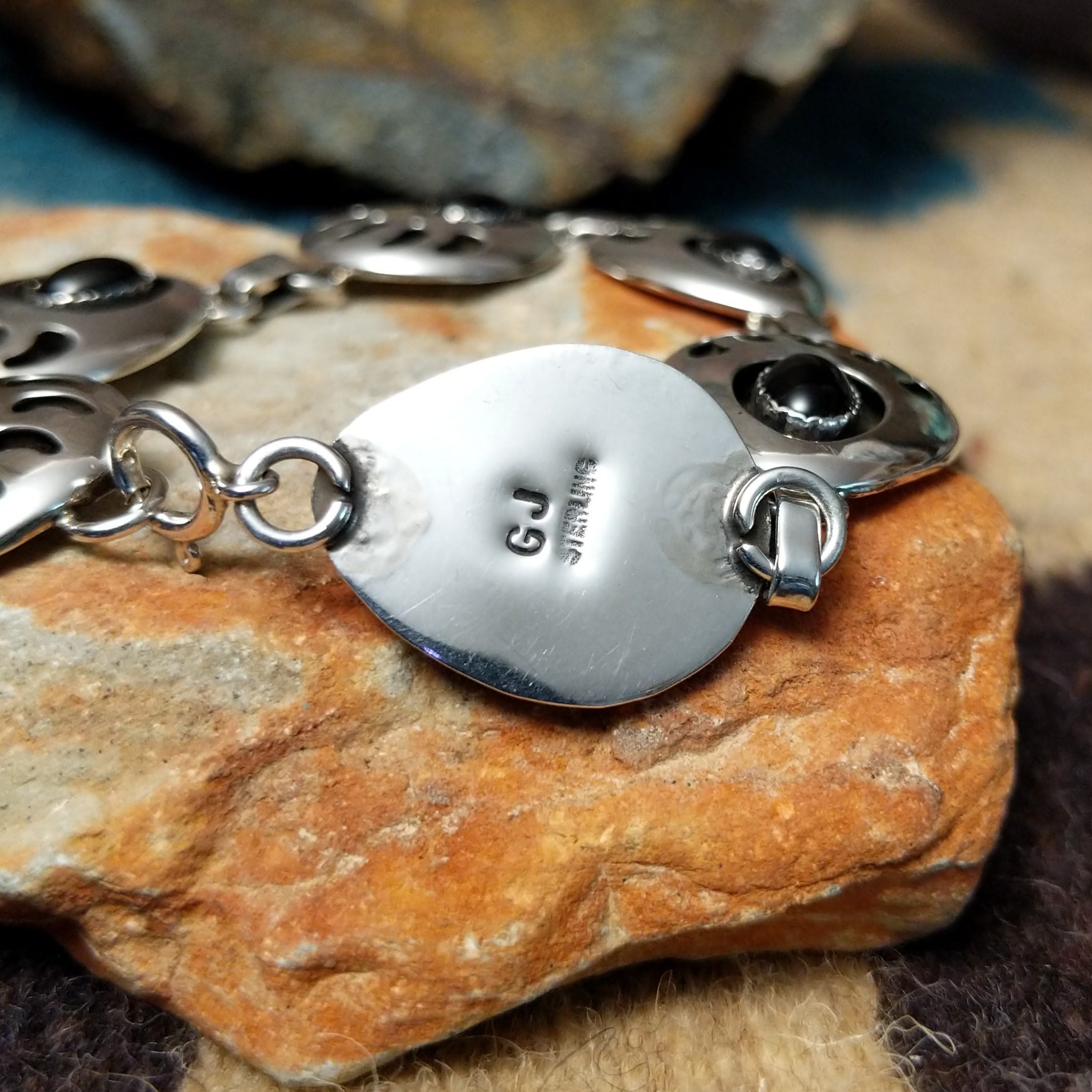 Sterling silver bear paw shadowbox bracelet by George Jones with a black onyx stone and hand-stamped Southwestern details; artisan and Sterling Silver stamp.