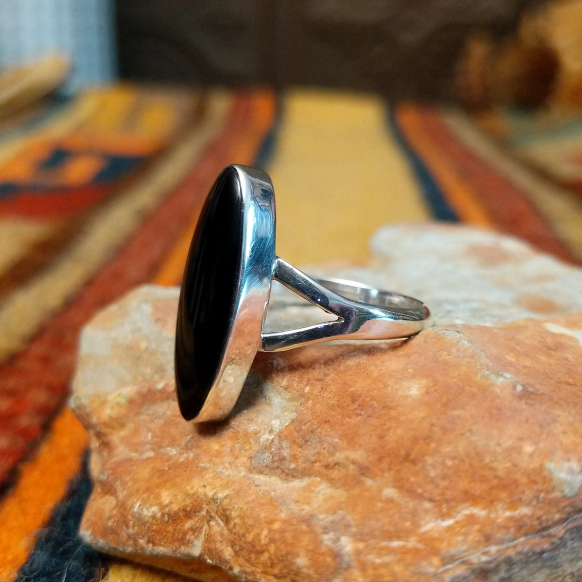 Black Onyx Ring by Cathy Webster featuring an elongated oval polished black onyx stone set in sterling silver with a smooth bezel and open split-shank band; side view.