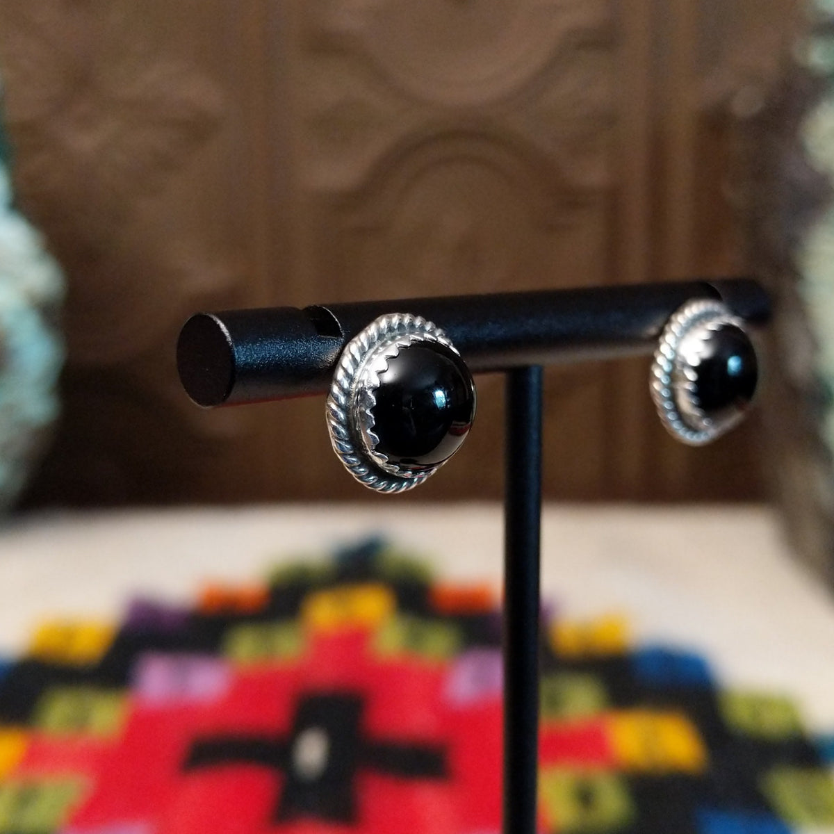 Black Onyx Round Earrings by Peggy Skeets featuring polished round black onyx cabochons set in silver with detailed twisted rope borders; side view.