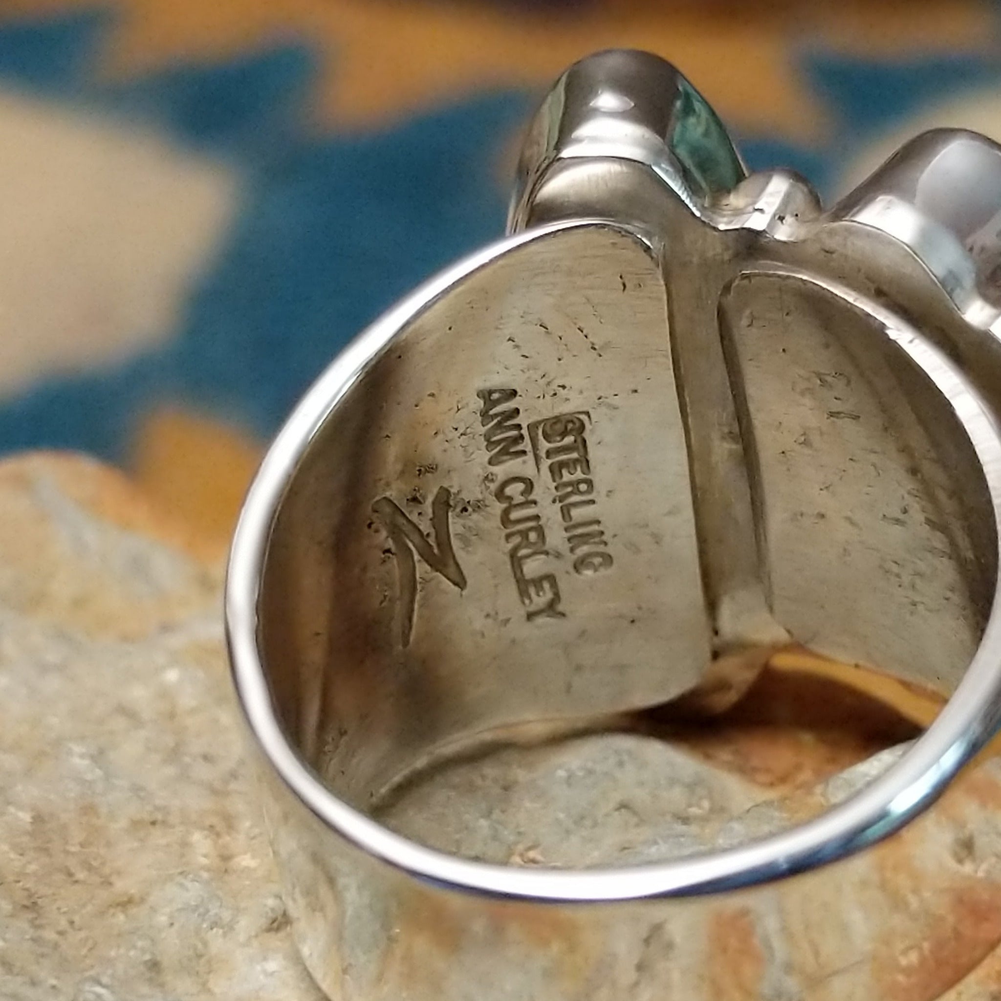 Handcrafted Navajo sterling silver ring by Ann Curley featuring three graduated oval black onyx cabochons in bezel settings with polished silver bead accents on a wide statement band; artisan and Sterling Silver stamp.