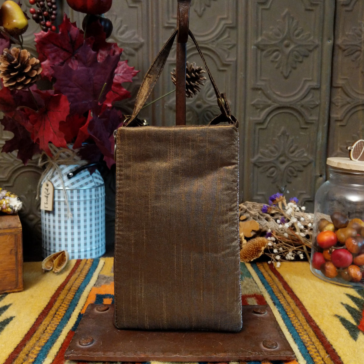 Boots & Spurs Club Bag by Bamboo Trading featuring intricately beaded brown and turquoise cowboy boots, a rustic American flag-inspired background, a sparkling blue star, and a brown shoulder strap; back side view.