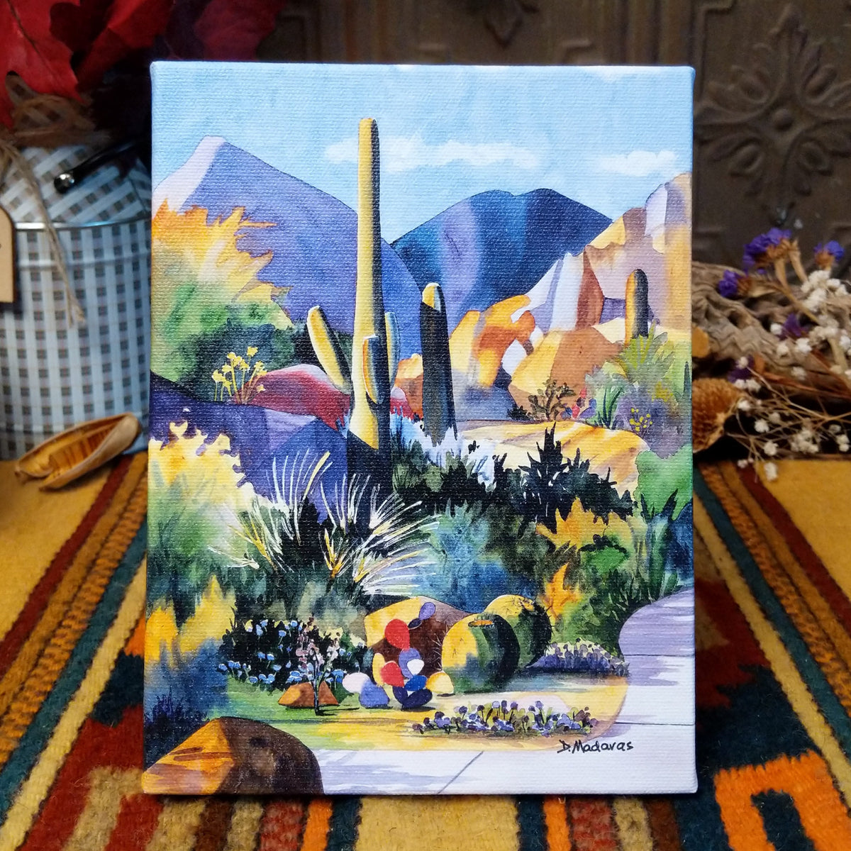Boulders 2 canvas artwork by Diana Madaras featuring towering saguaro cacti, colorful desert boulders, distant mountains, and vibrant Southwestern vegetation in shades of blue, purple, green, and yellow.