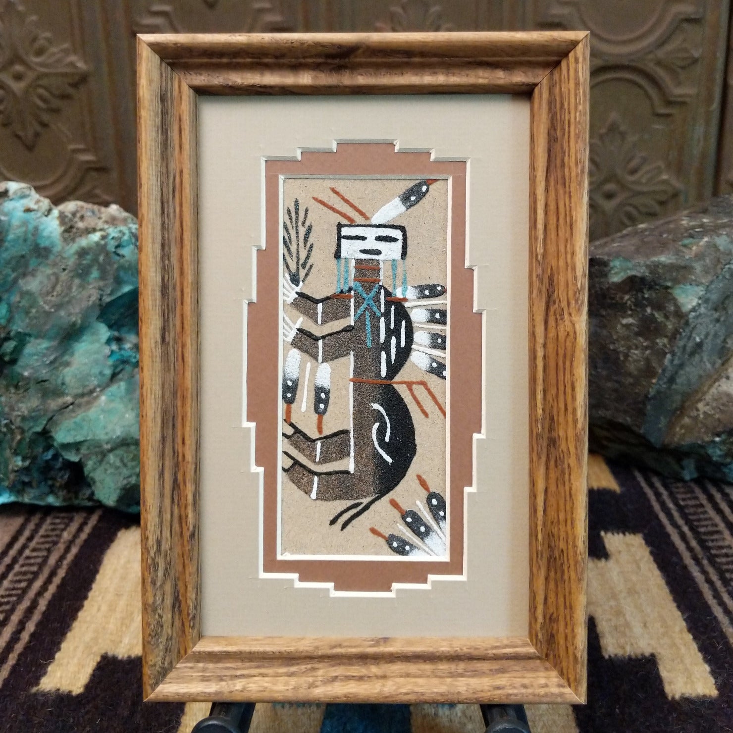Framed Navajo sand painting of a stylized buffalo with feather motifs.