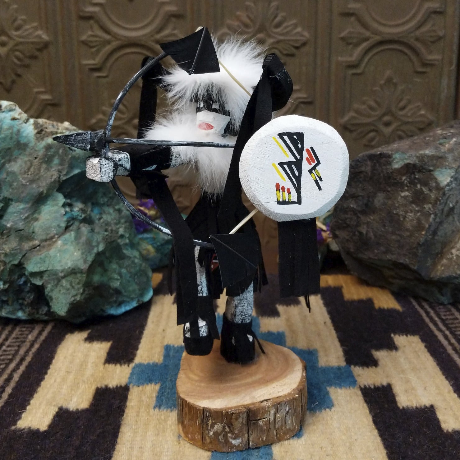 Navajo-made Buffalo Warrior kachina doll by M. C. with black garments, white fur collar, bow and arrow, and painted shield.
