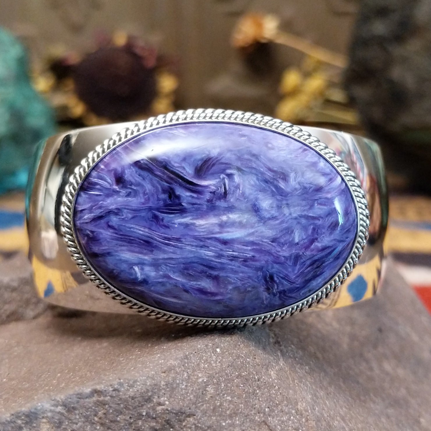 Sterling silver cuff featuring an oval charoite stone framed by a twisted rope bezel.