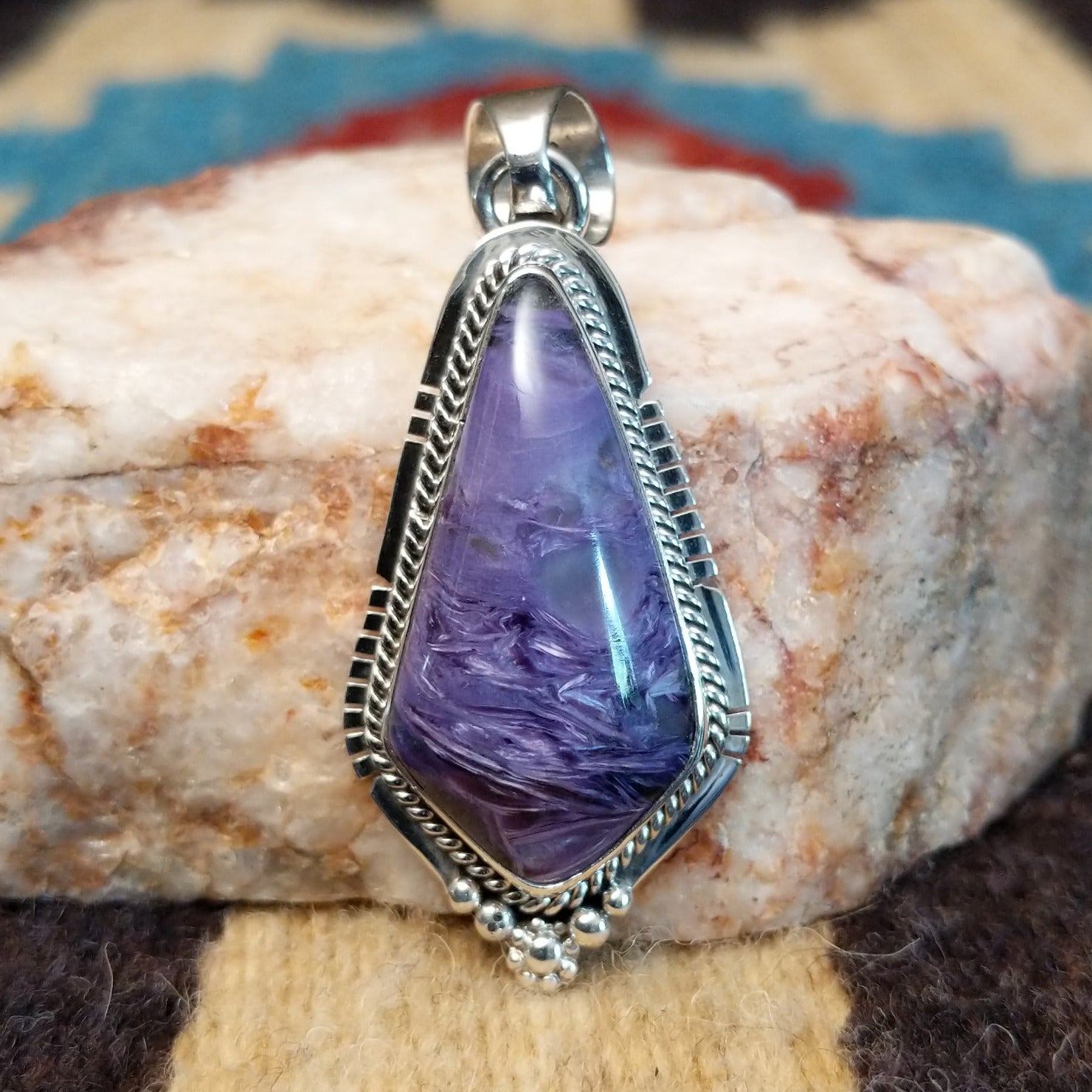 Sterling silver pendant with charoite set in a shield-shaped bezel, framed by twisted rope and dotted accents.