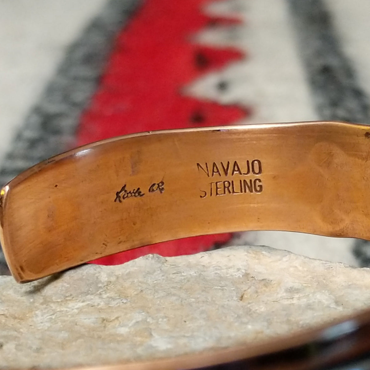 Copper and silver cuff by Robert Little featuring a repeating stamped bush-inspired pattern with oxidized detailing, framed by polished copper borders; artisan and Sterling Silver stamp.
