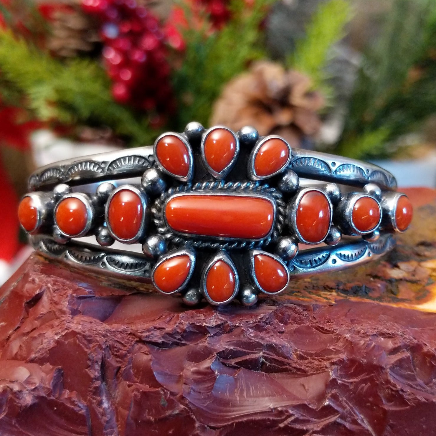 Sterling silver cuff with clusters of red coral, twisted rope accents, and scalloped stamps.