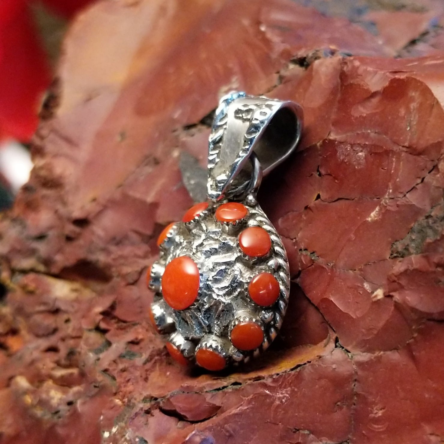 Sterling silver flower pendant with coral set in notched bezels and hammered finish.