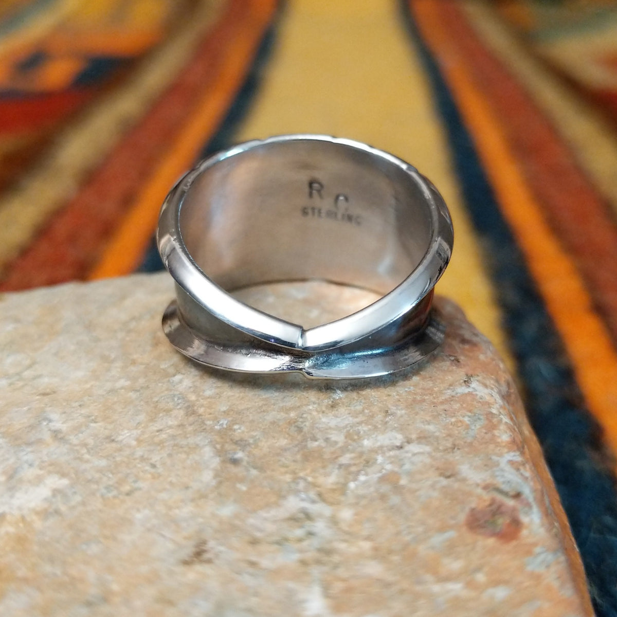 This striking Coral Trio Ring by Reed Charley features three rectangular red-orange coral stones in sawtooth silver bezels, accented by polished silver beads and a wide oxidized silver band; underside view.