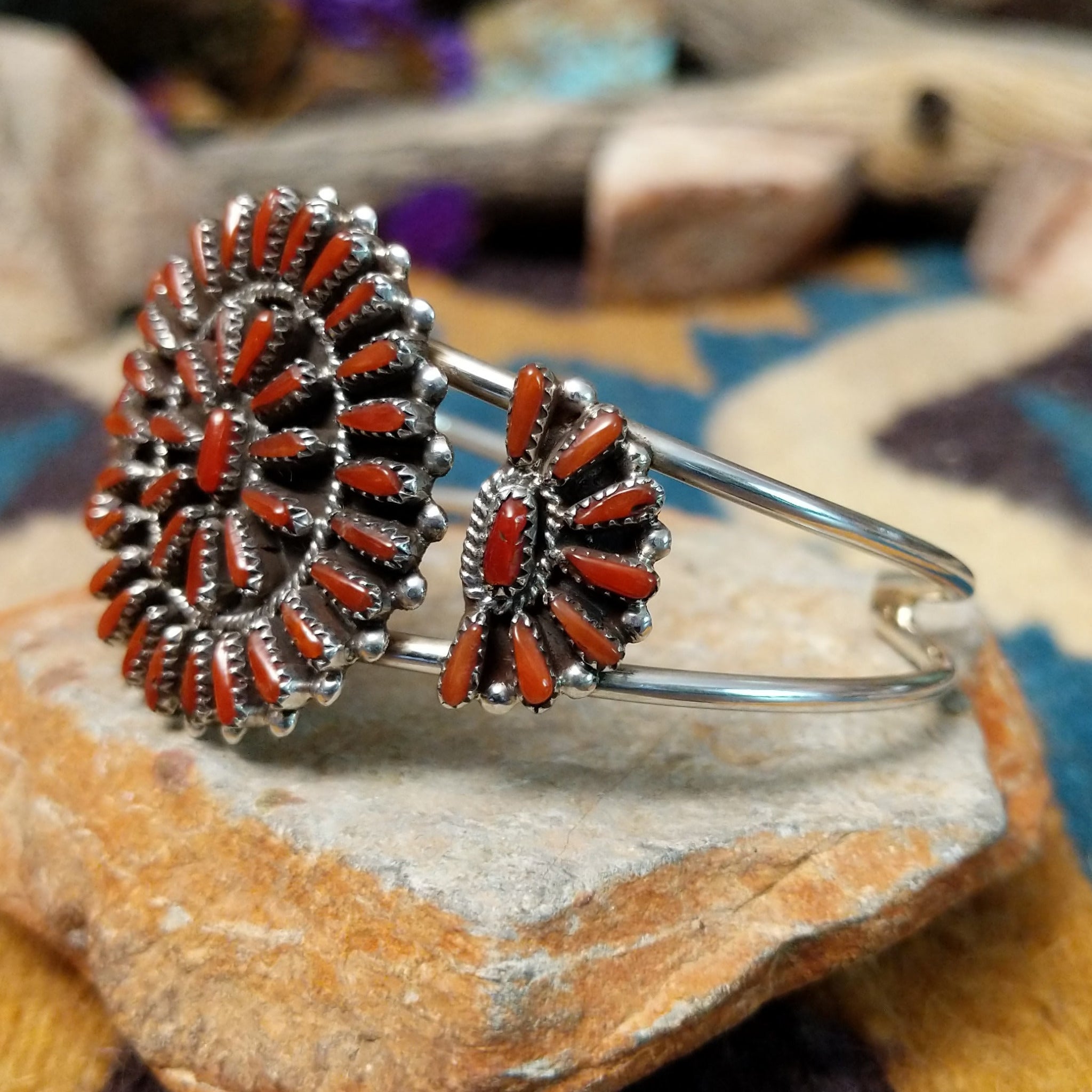 Handcrafted sterling silver cuff by Judy Wallace featuring a coral petitpoint concho centerpiece with matching side conchos, twisted rope detailing, silver bead accents, and a triple-shank cuff; side view.