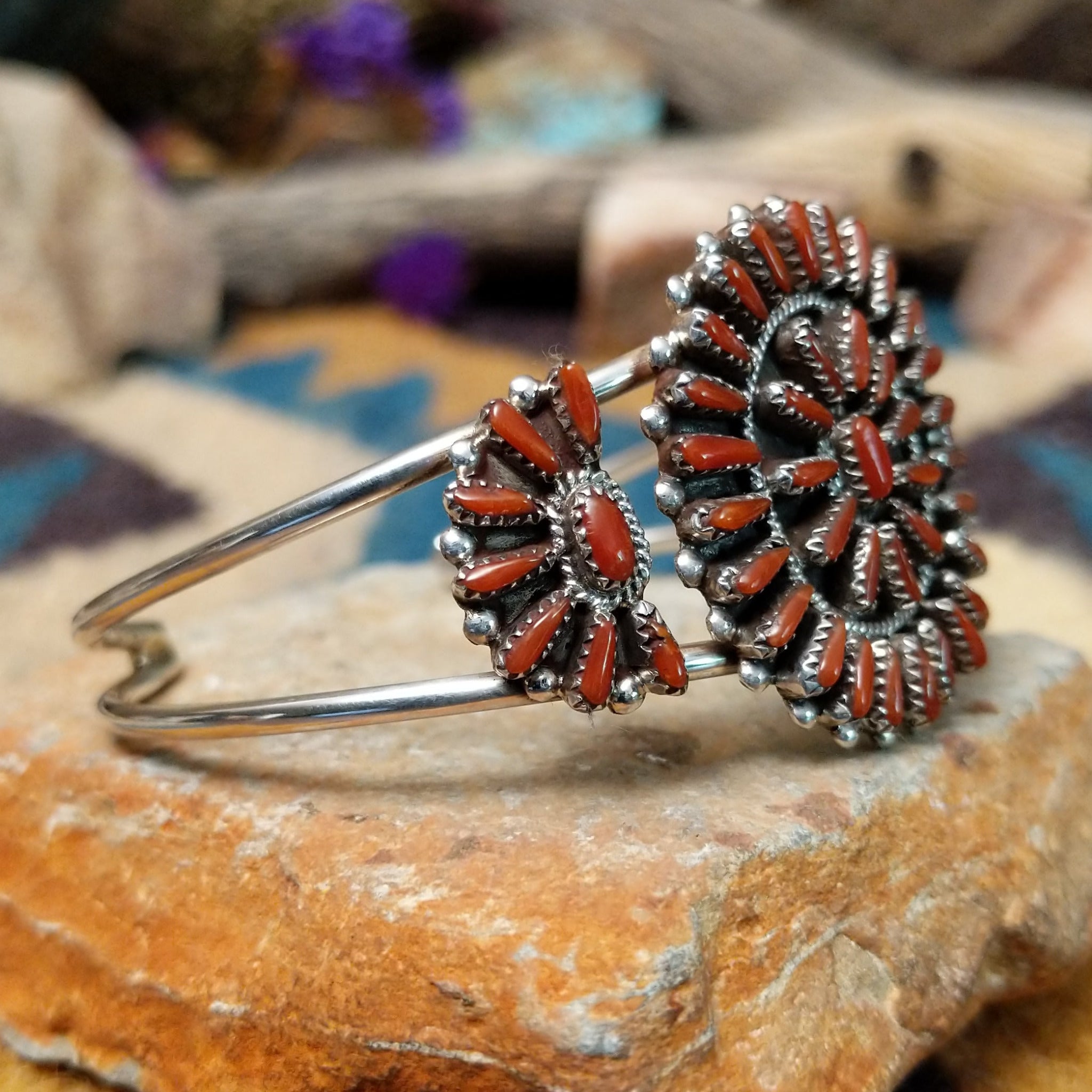 Handcrafted sterling silver cuff by Judy Wallace featuring a coral petitpoint concho centerpiece with matching side conchos, twisted rope detailing, silver bead accents, and a triple-shank cuff; side view.