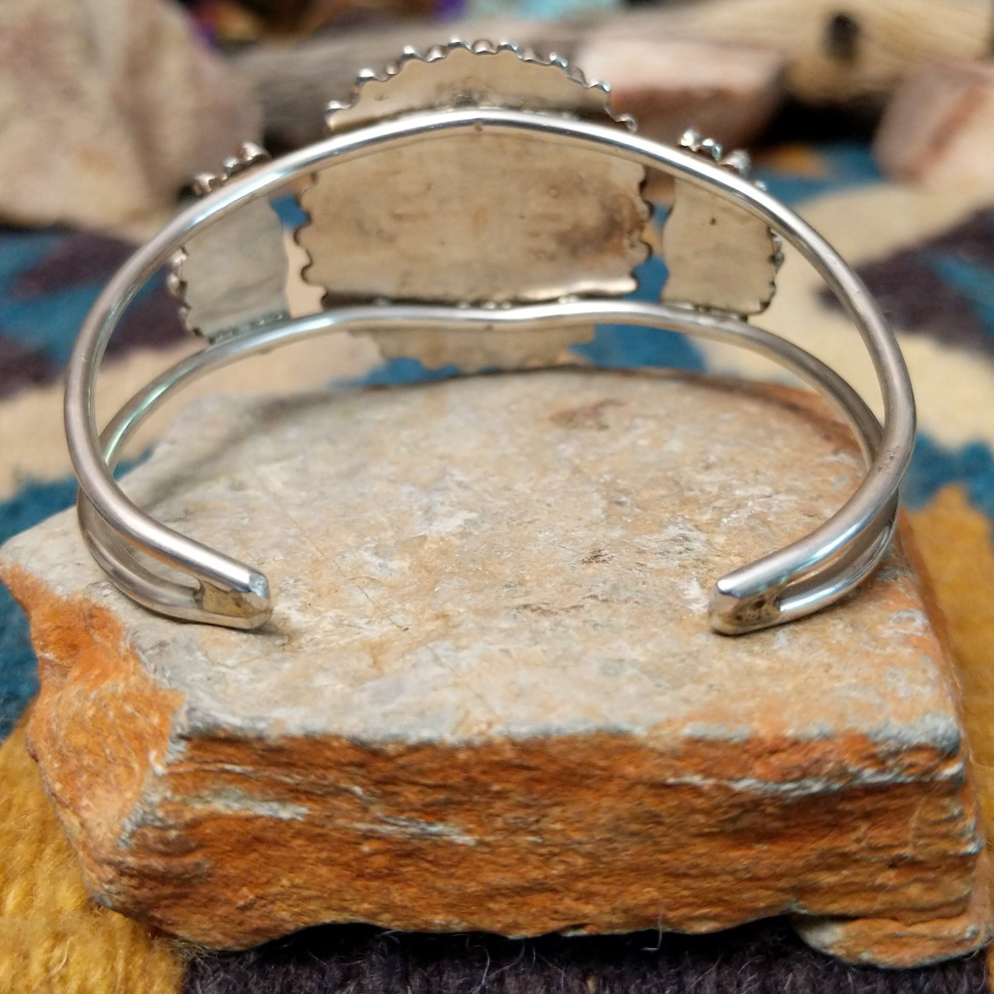 Handcrafted sterling silver cuff by Judy Wallace featuring a coral petitpoint concho centerpiece with matching side conchos, twisted rope detailing, silver bead accents, and a triple-shank cuff; underside view.