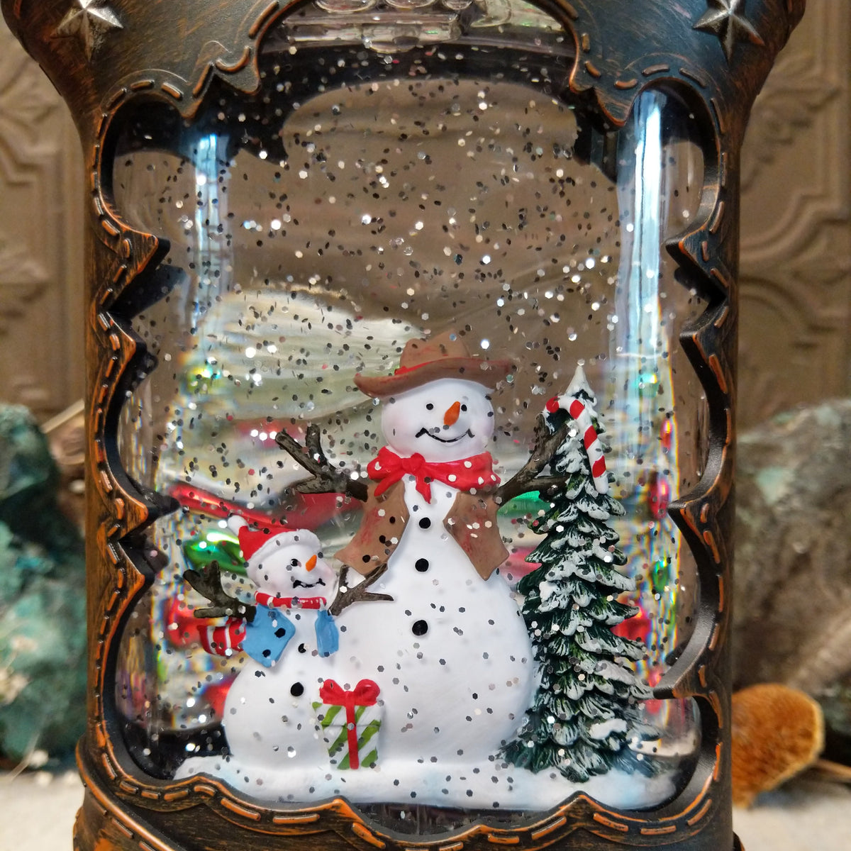 Cowboy Boot Snowmen Snow Globe featuring two snowmen and a snowy evergreen tree inside a rustic brown Western boot decorated with silver stars and studs.