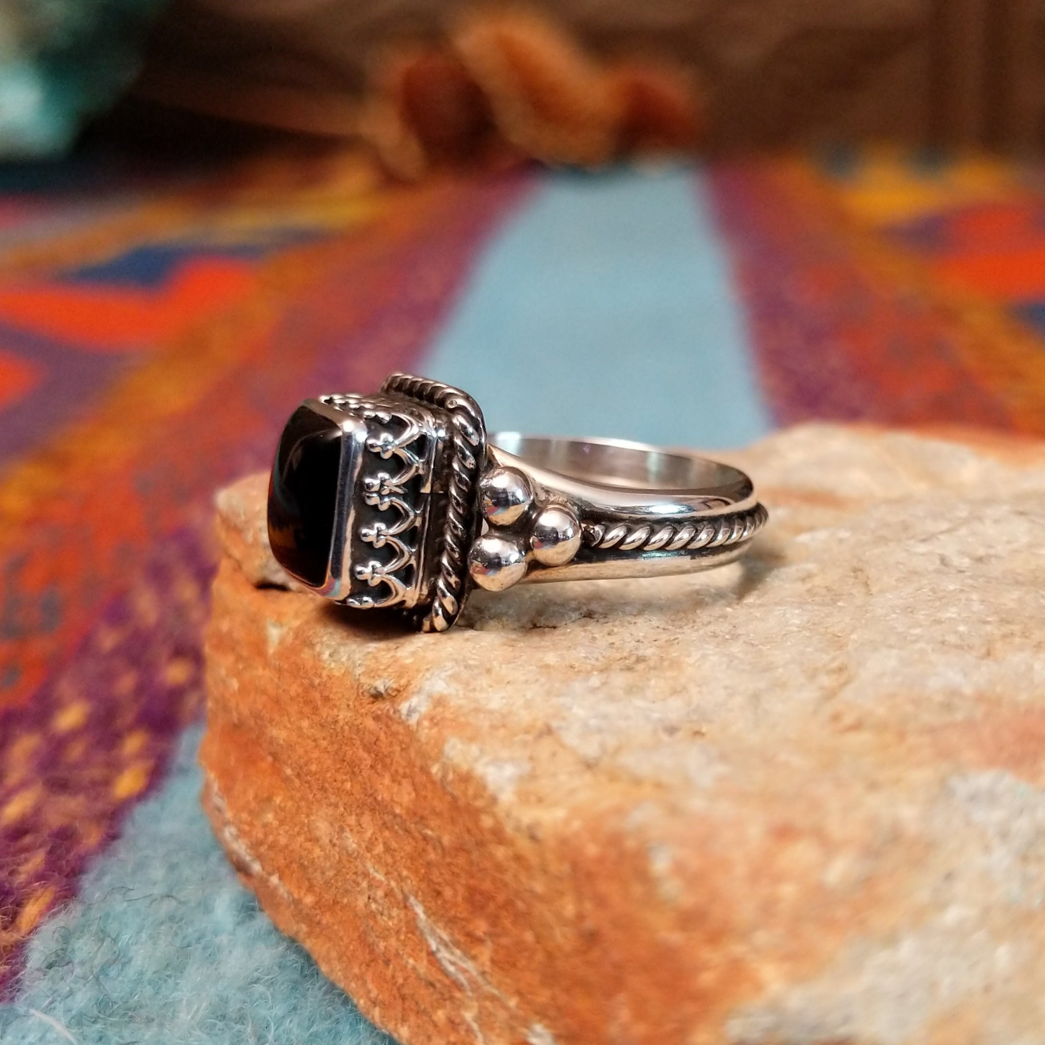 Black onyx silver ring by Angela Martin with twisted border and silver drop accents.
