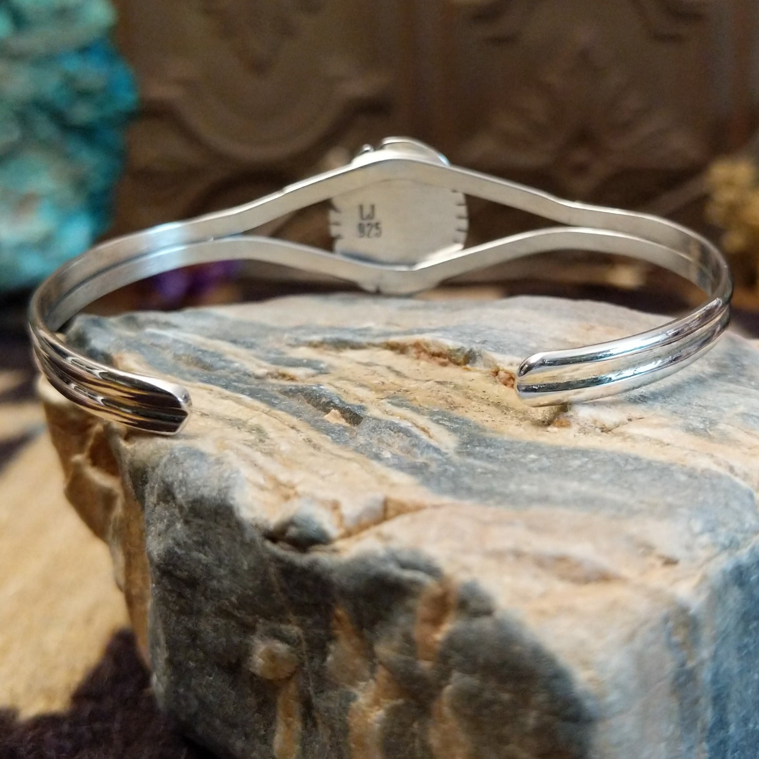 Sterling silver bracelet with turquoise set in an oval bezel, framed by twisted rope and an incised setting.