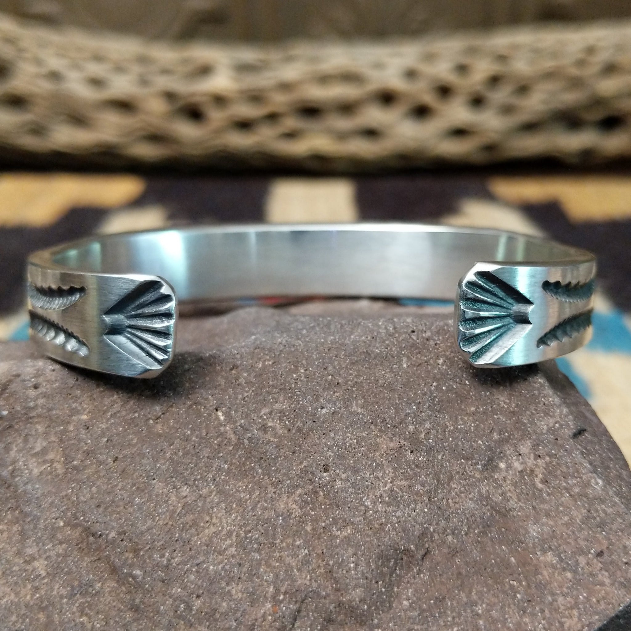 Deep stamped sterling silver cuff by Jerrold Tahe, featuring bold hand-stamped patterns with deep texture on a handcrafted open sterling silver cuff. Underside view.