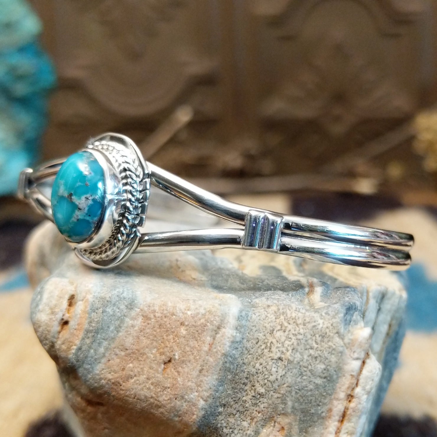 Sterling silver bracelet with turquoise set in an oval bezel, framed by twisted rope and incised accents.