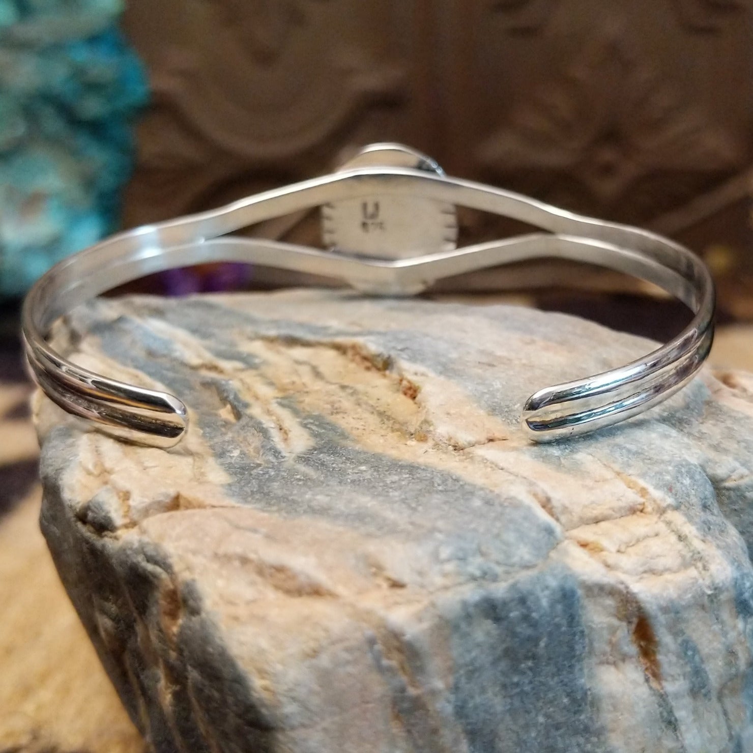 Sterling silver bracelet with turquoise set in an oval bezel, framed by twisted rope and incised accents.