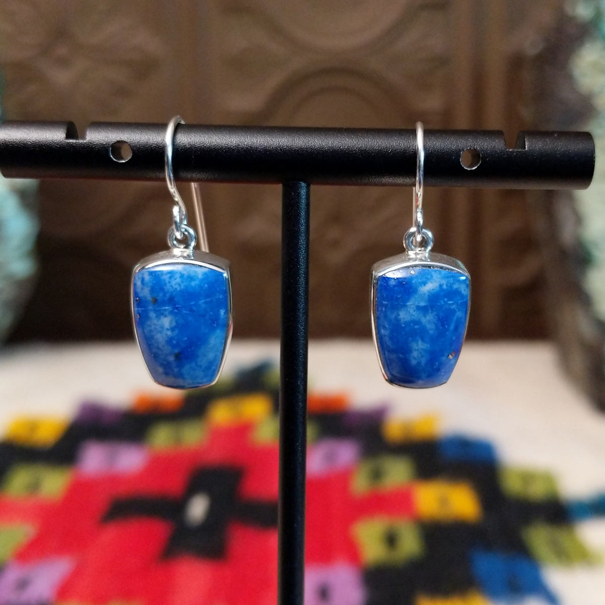 Denim Lapis Earrings by Cathy Webster featuring polished blue stones with cloudy light-blue and white variations, set in smooth silver bezels and suspended from French ear wires.