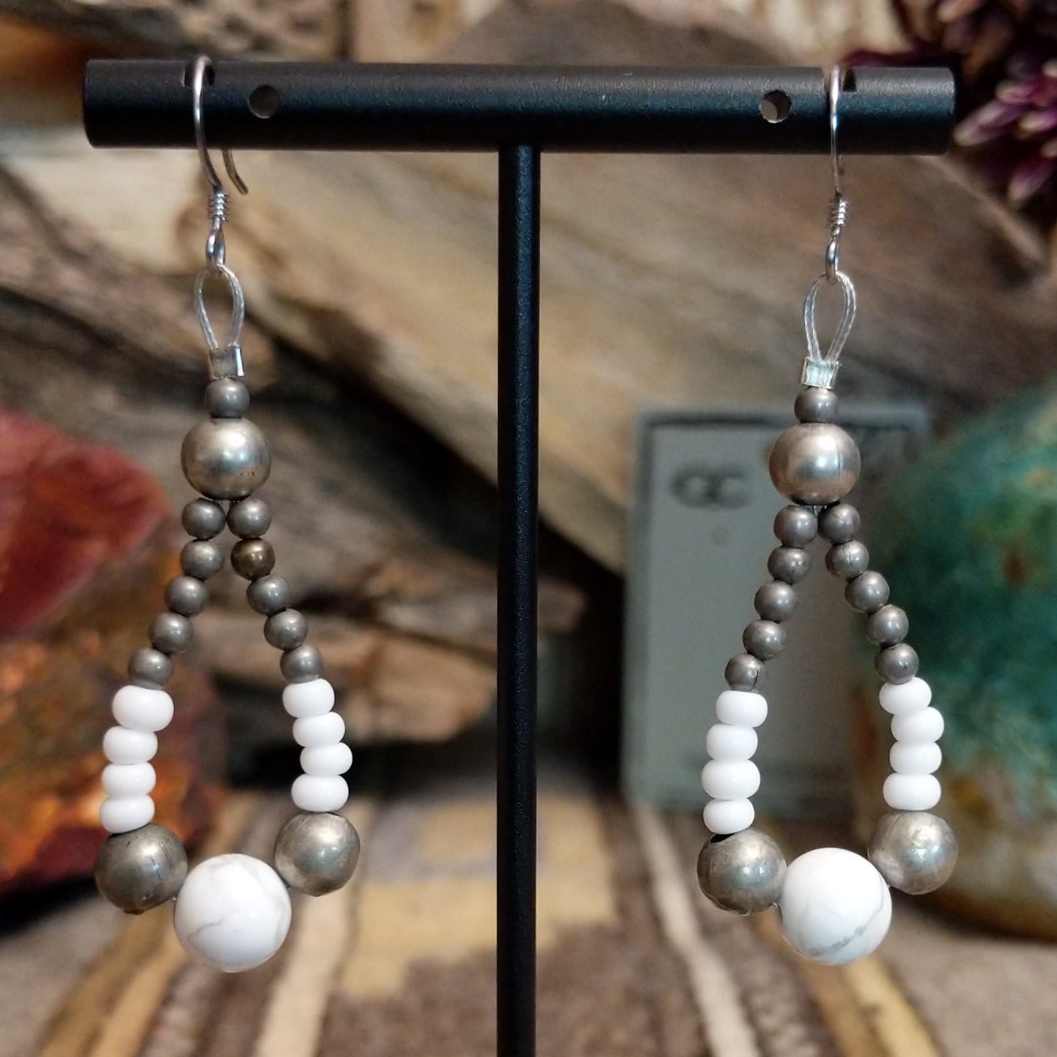 A pair teardrop earrings, featuring a mix of silver and white beads with a central white stone.