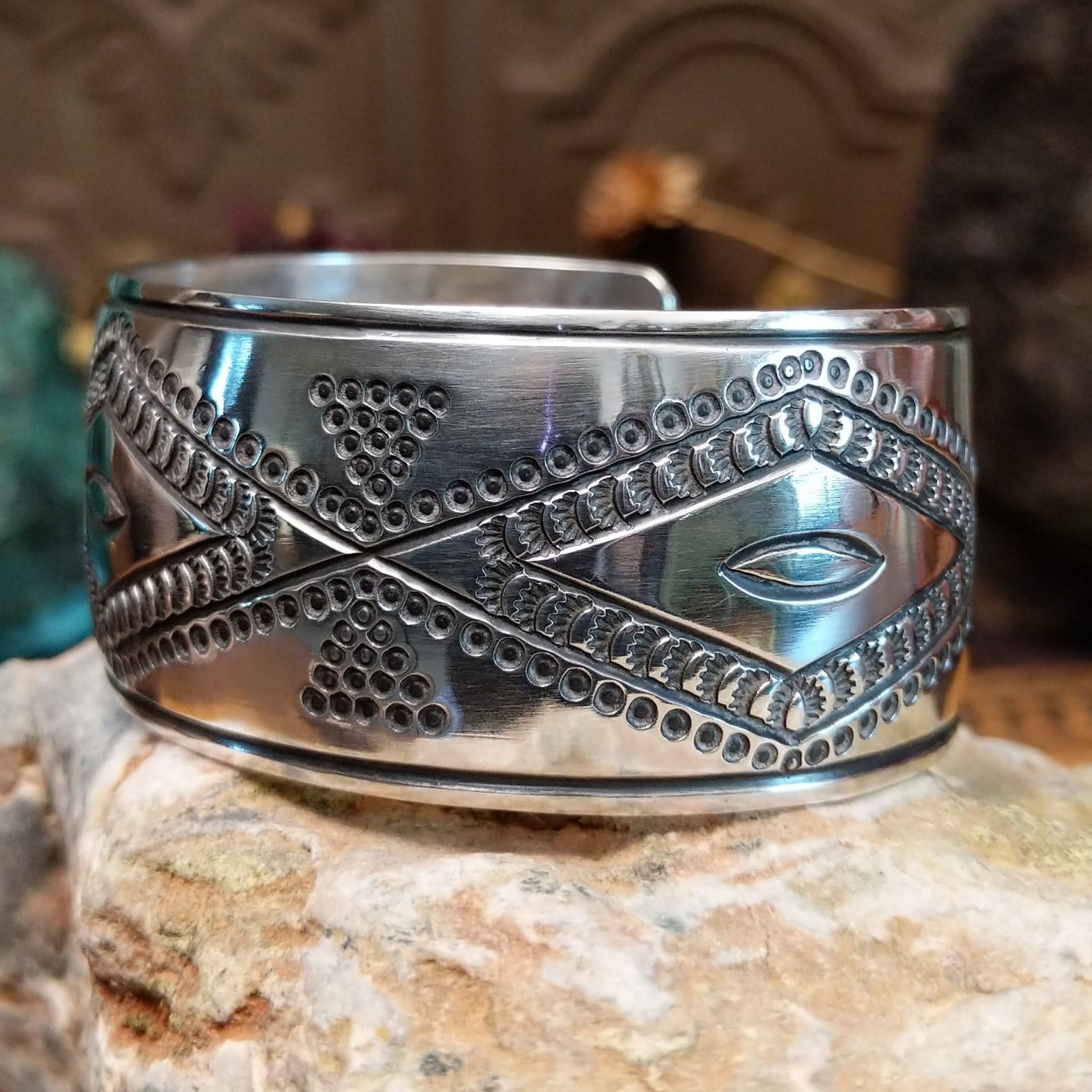 Wide sterling silver cuff bracelet with raised geometric silverwork, hand-stamped details, and oxidized accents.
