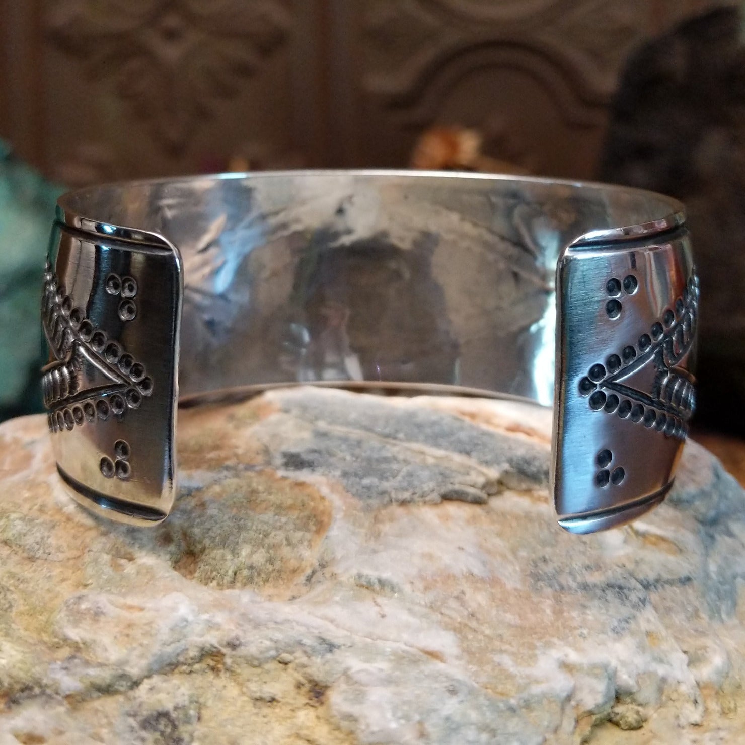 Wide sterling silver cuff bracelet with raised geometric silverwork, hand-stamped details, and oxidized accents.