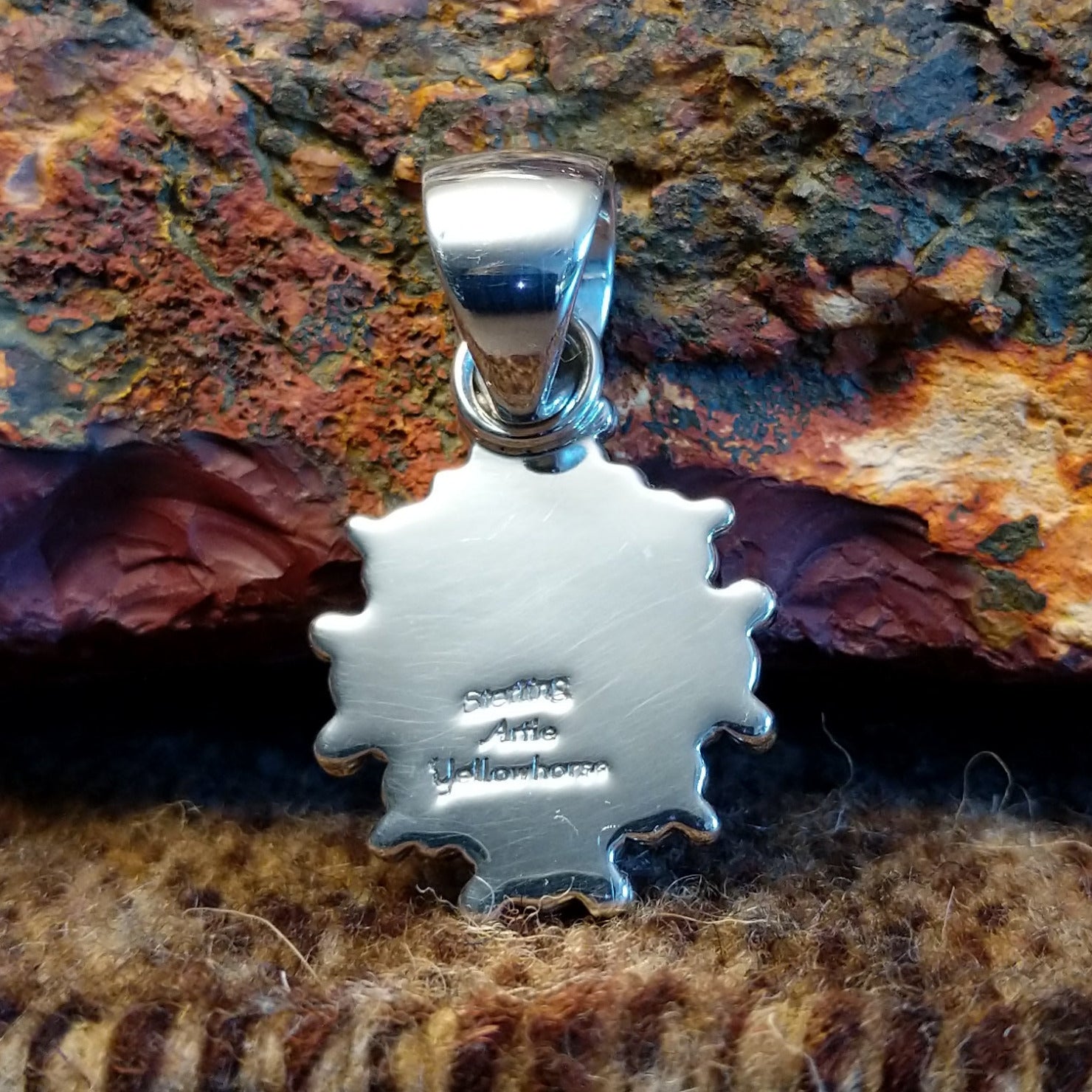The back of the pendant features the artisan's stamped signature.