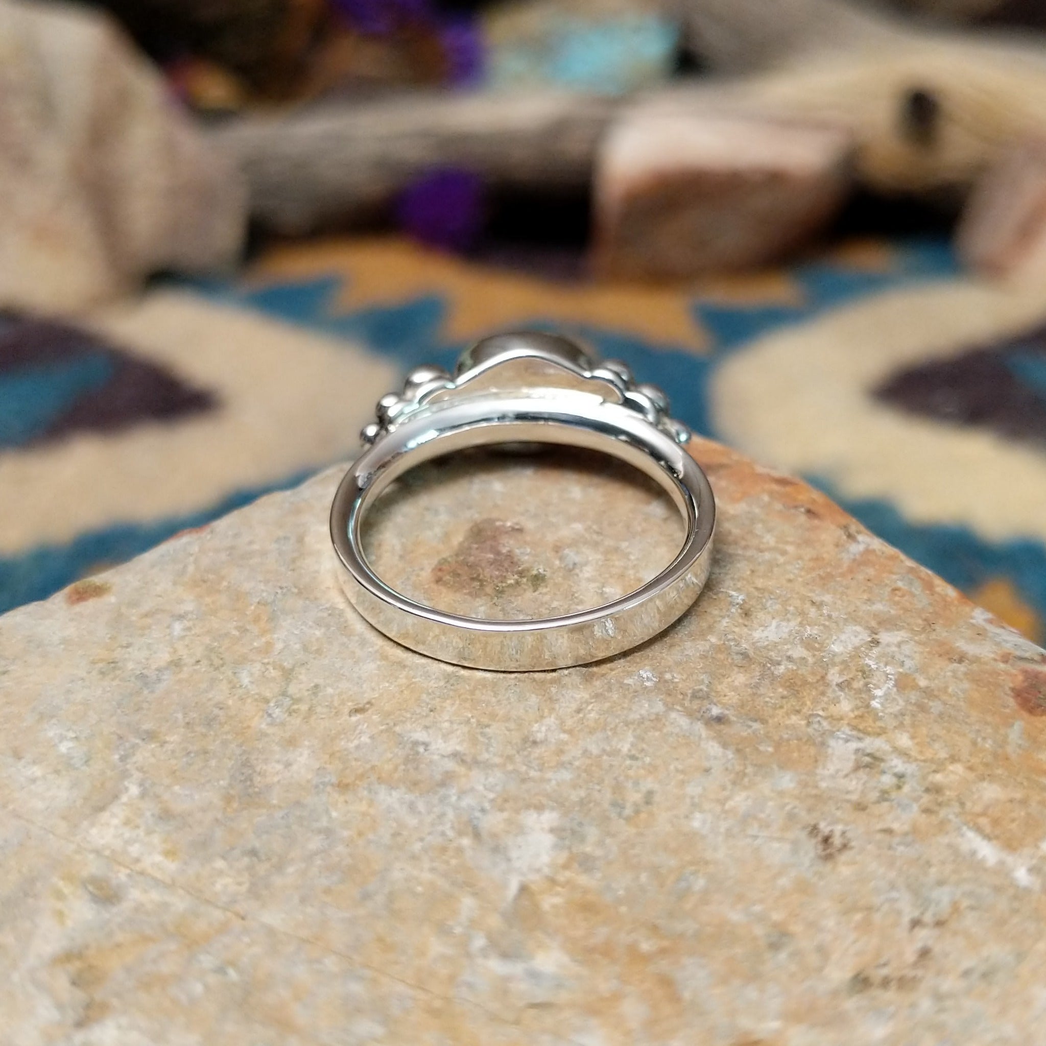 Handcrafted sterling silver Navajo ring featuring a polished oval Black Onyx cabochon in a smooth bezel setting, accented by decorative sterling silver bead clusters on each side of the gemstone; underside view.