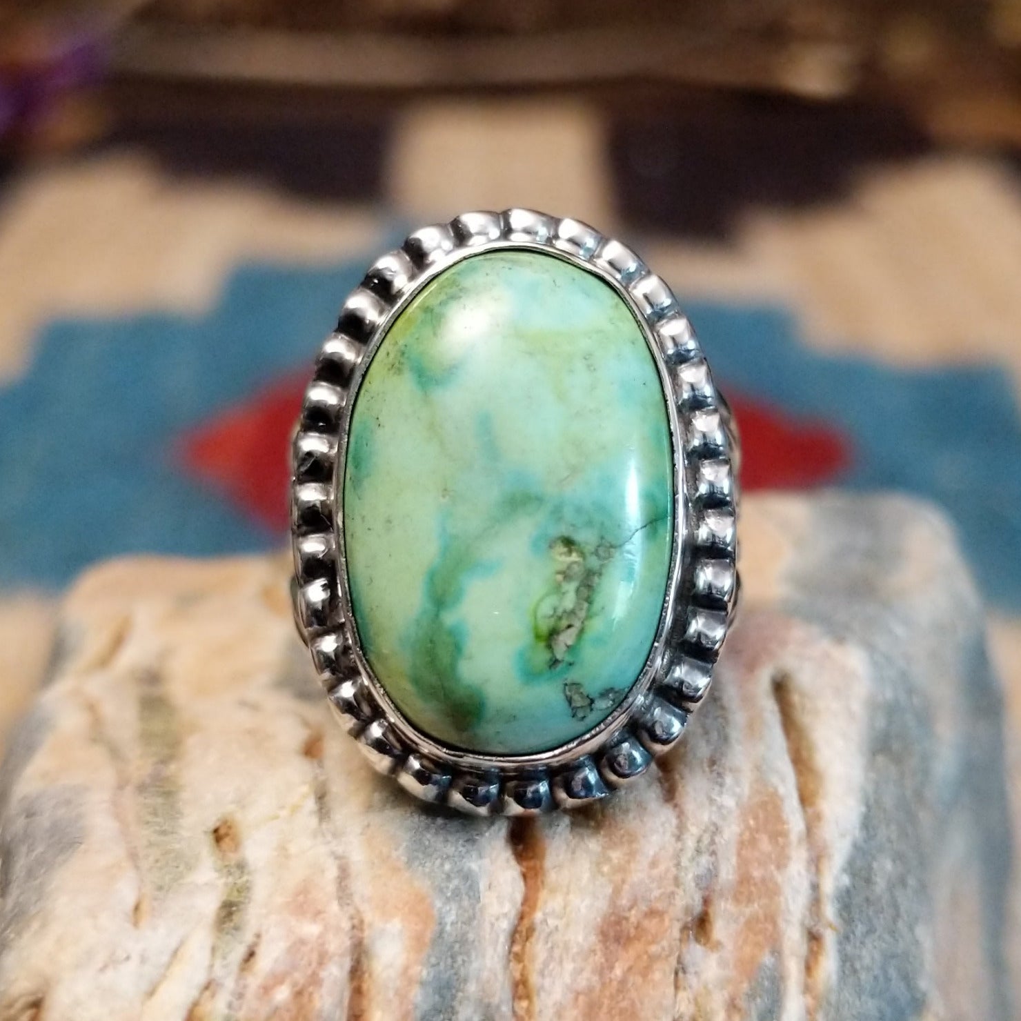 Sterling silver ring with Sonoran gold turquoise set in a large, oval bezel that is framed by dotted accents.