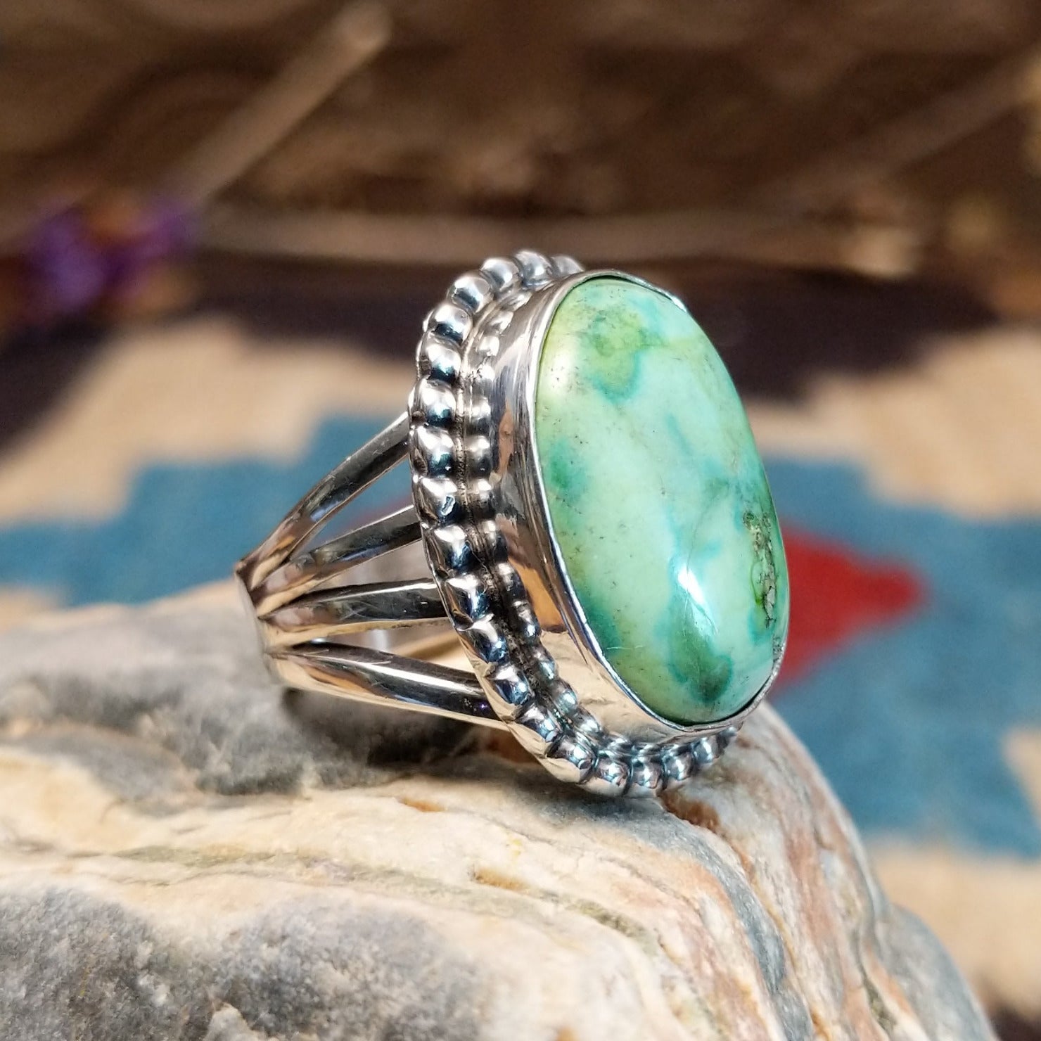 Sterling silver ring with Sonoran gold turquoise set in a large, oval bezel that is framed by dotted accents.