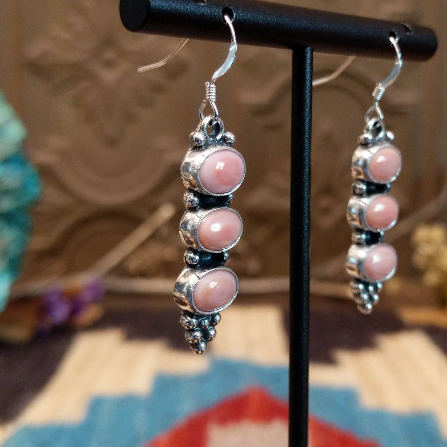 Sterling silver earrings with pink conch shells set in three bezels, framed by dotted accents.