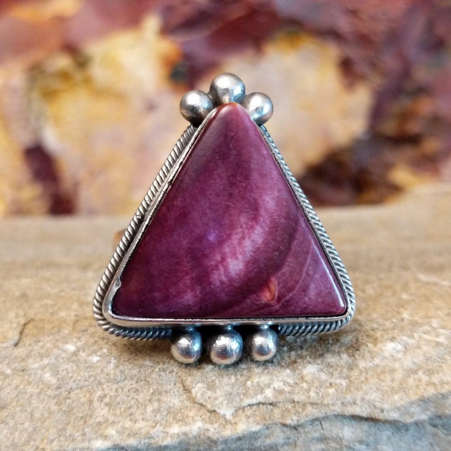 Triangular purple spiny oyster shell with twisted rope accent and dotted embellishments.
