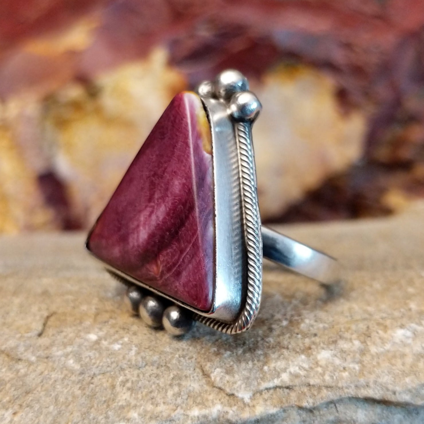 Triangular purple spiny oyster shell with twisted rope accent and dotted embellishments.