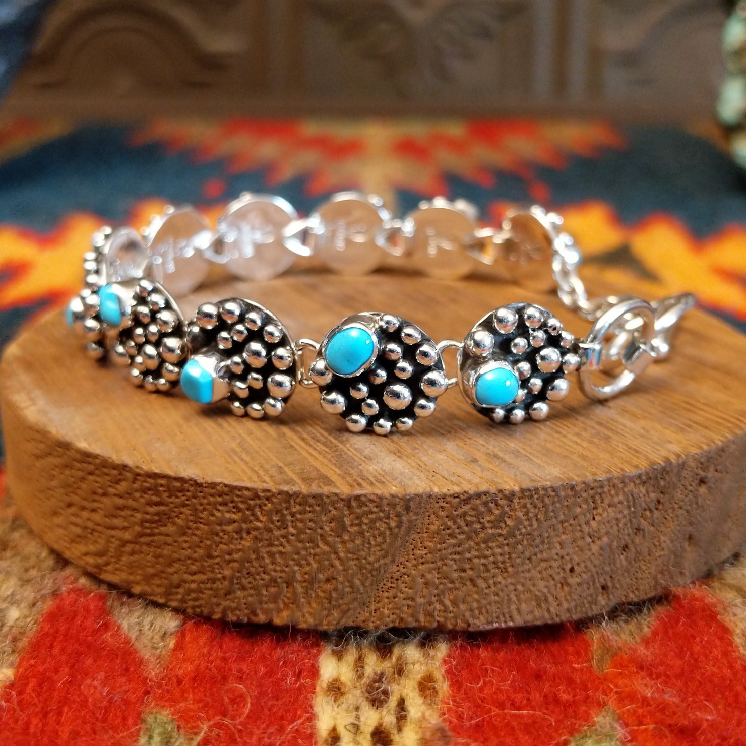 Sterling silver bracelet with dotted settings and turquoise set in small, round bezels.